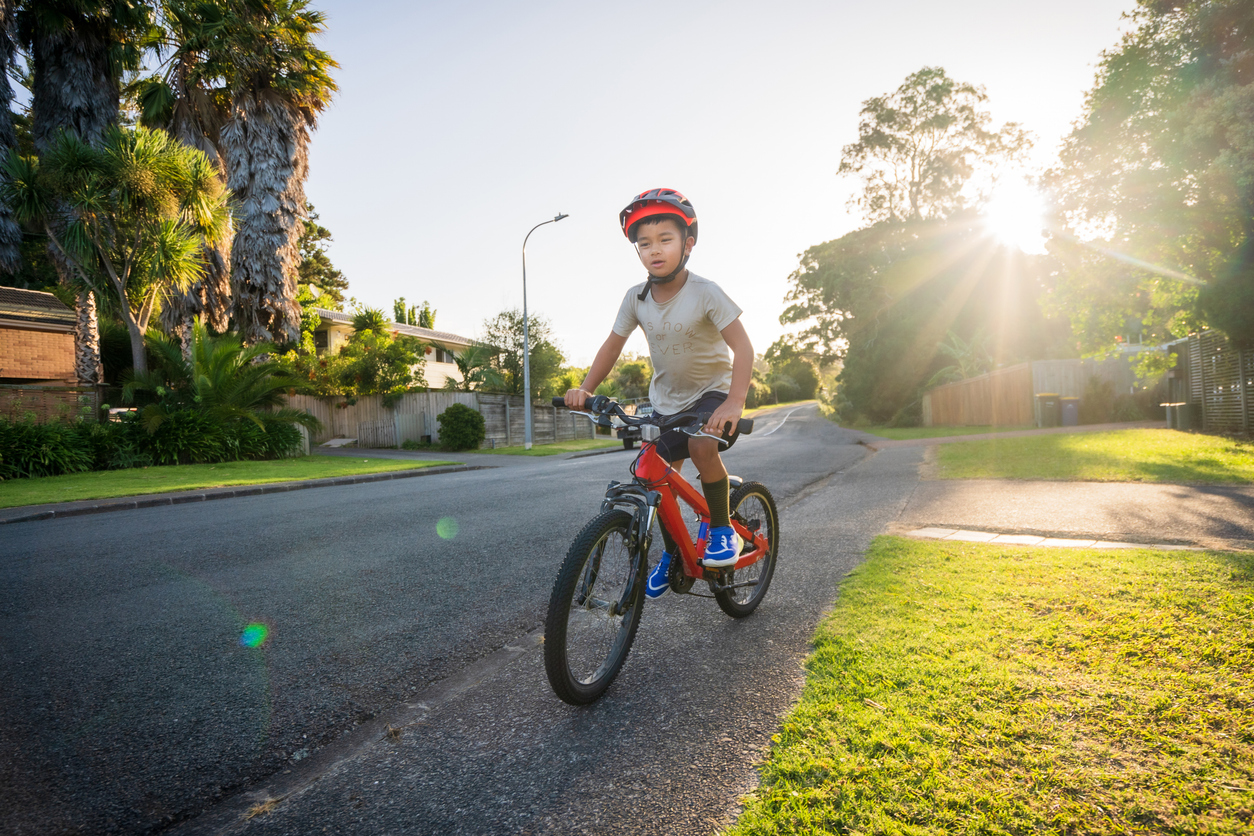 A kid rides a bike on a footpath in Auckland. 