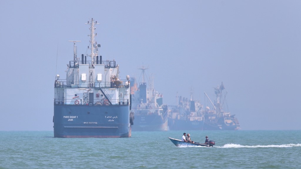 A small motorboat passes anchored vessels in the Strait of Hormuz off Bandar Abbas, Iran. (Source: Amirhosein Khorgooi/ISNA via AP)