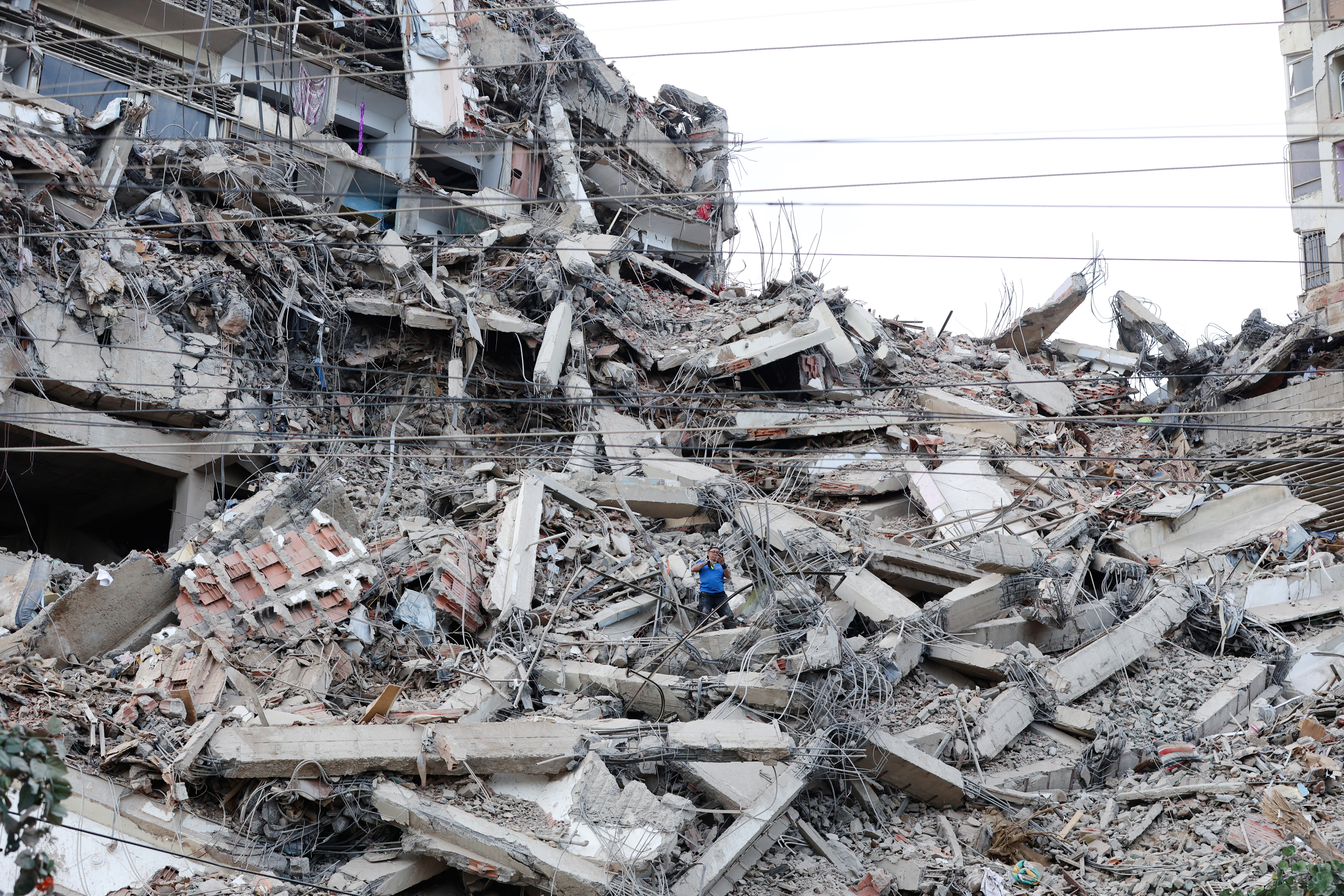 A man walks among the rubble of a building that collapsed in earthquakes the previous day in La Guaira, Venezuela