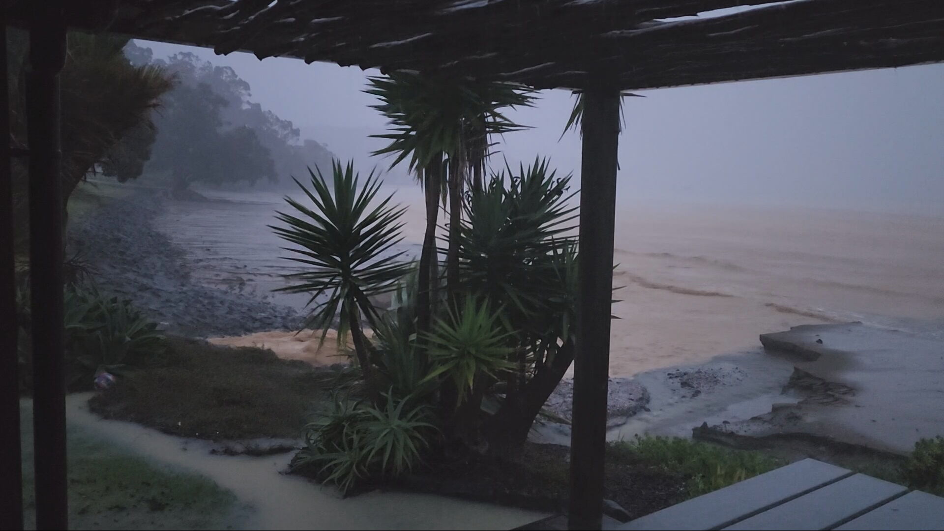Floodwater rages past a beach house at Ohawini Bay, Whangaruru.