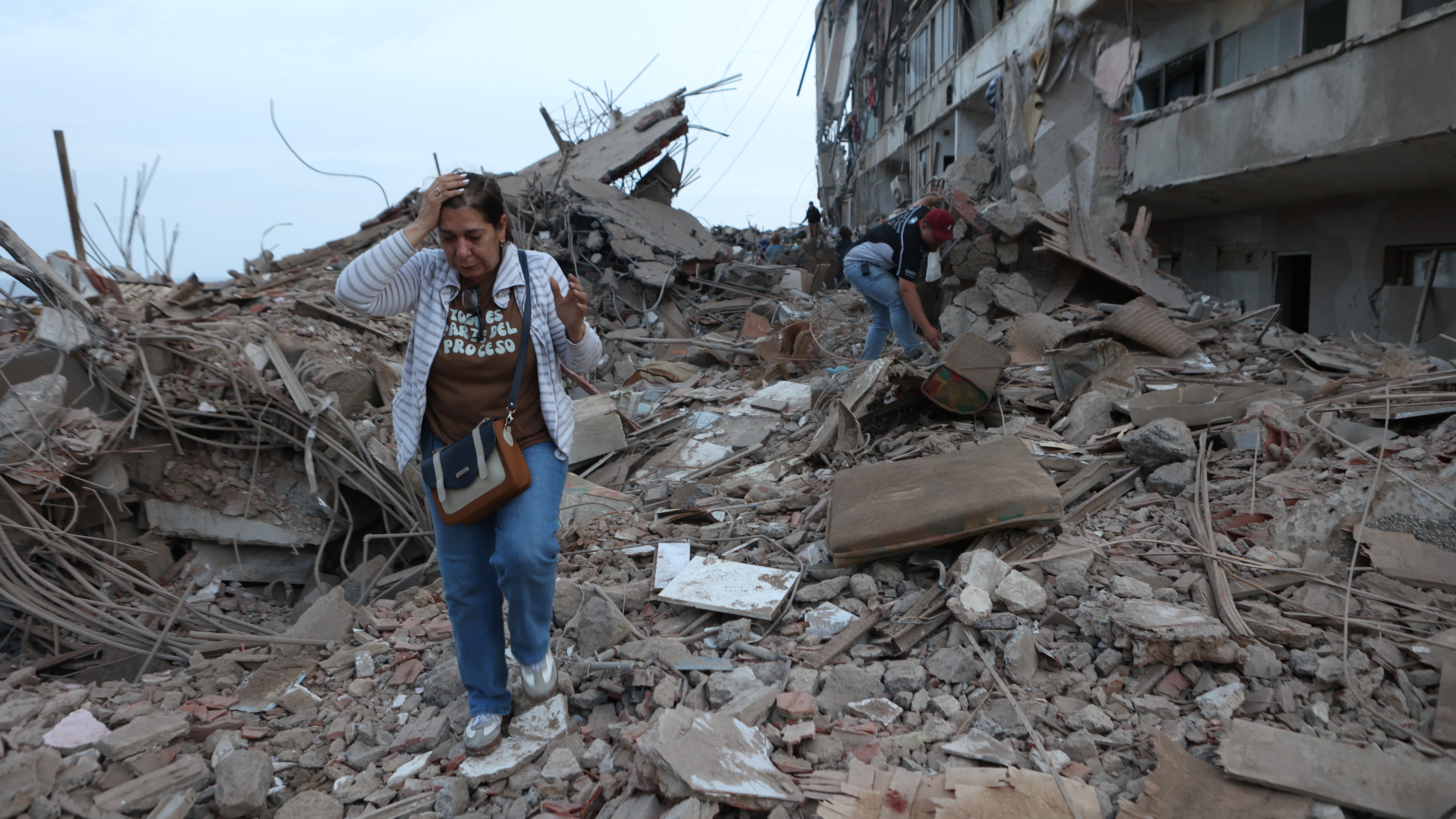 Residents walk among the rubble of building damaged in earthquakes the previous day in Catia La Mar, Venezuela.