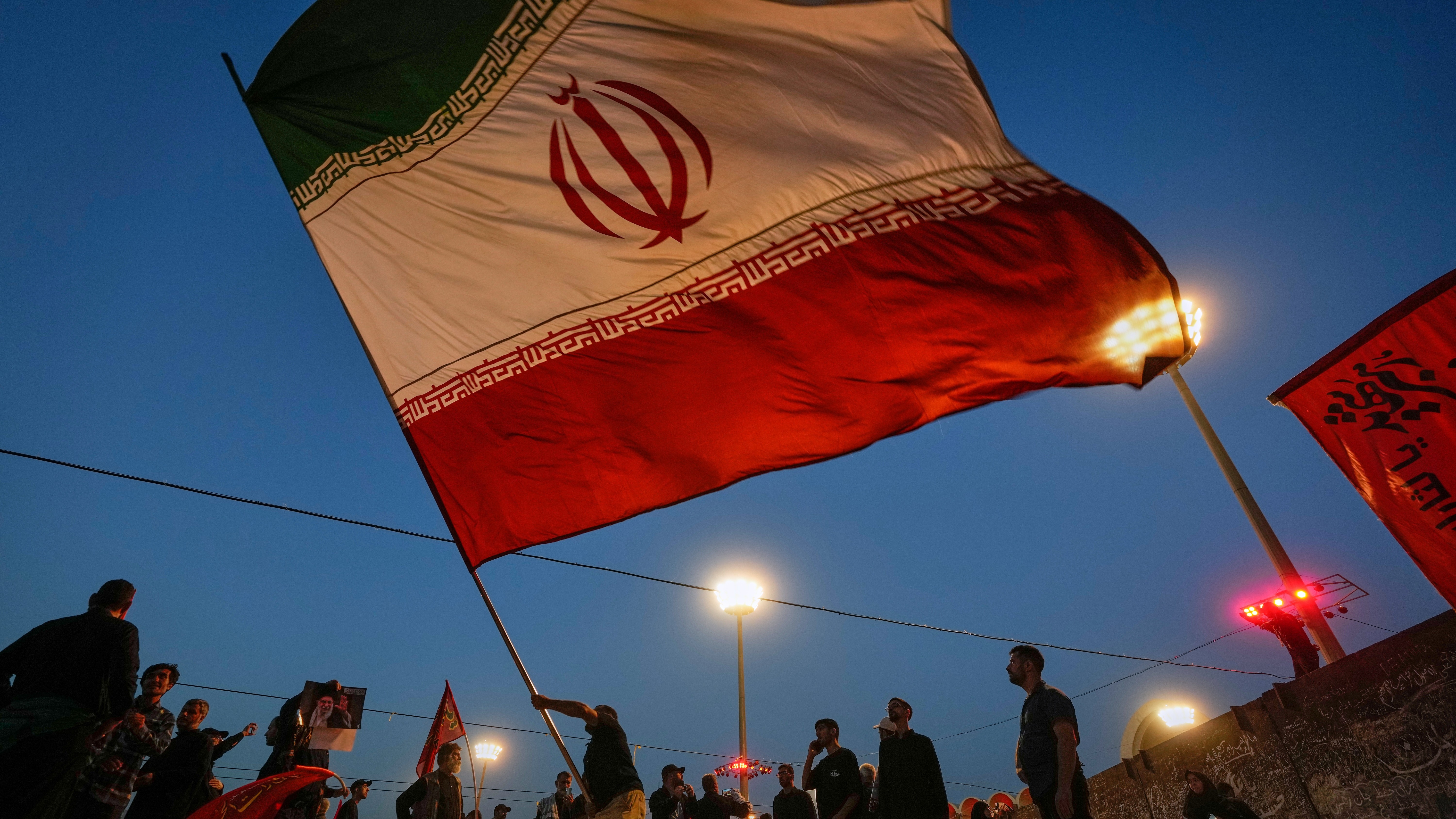 A man waves an Iranian flag during funeral ceremonies for slain Iranian Supreme Leader Ayatollah Ali Khamenei and members of his family at Imam Khomeini Mosalla Grand Mosque in Tehran, Iran.