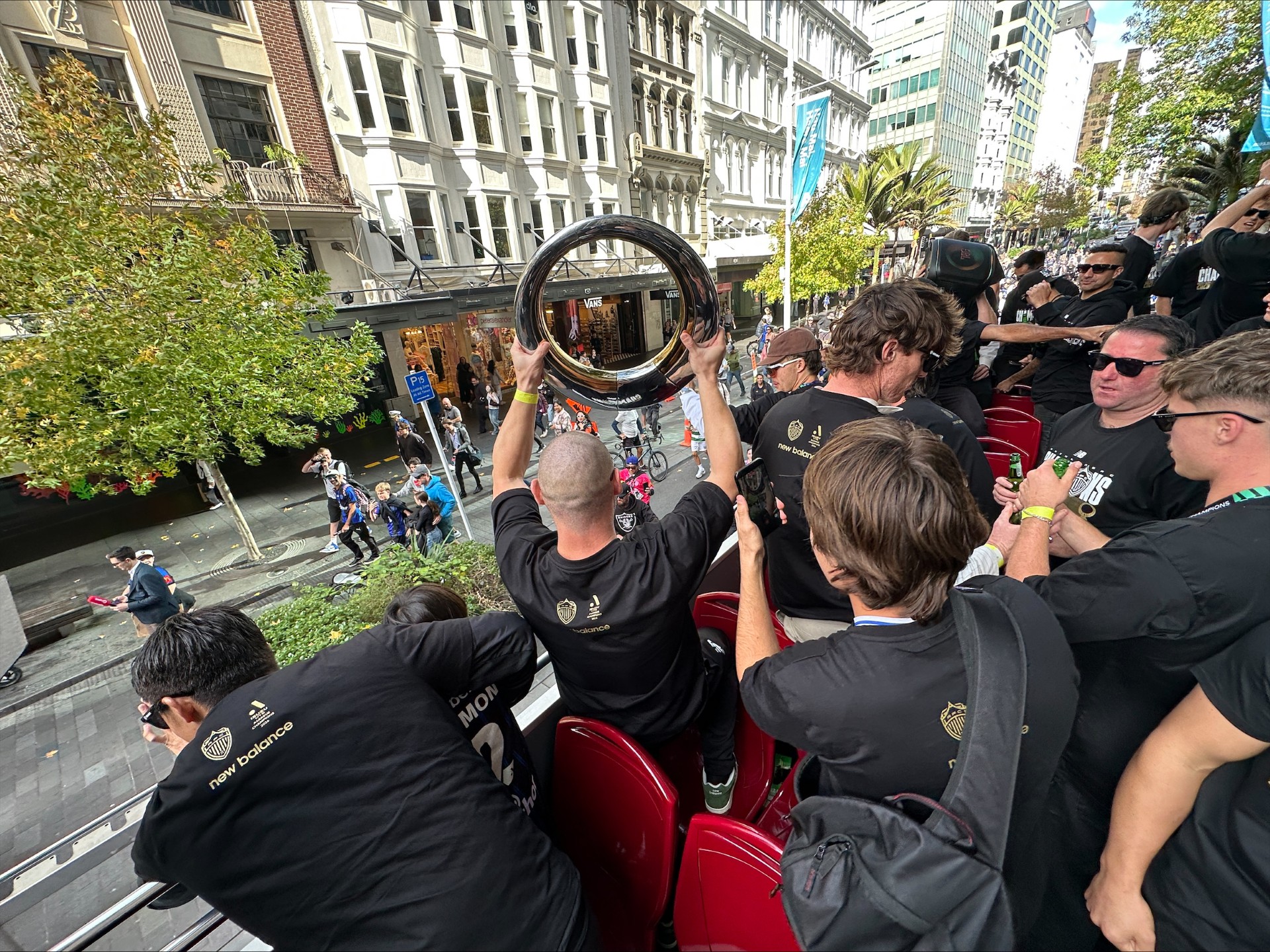 Auckland FC player waves trophy at fans.