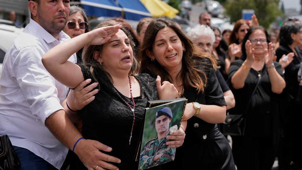 Rozette, second left, the wife of Lebanese army captain Elie Khoury, who was killed on Saturday in an Israeli airstrike, salutes during his funeral procession.