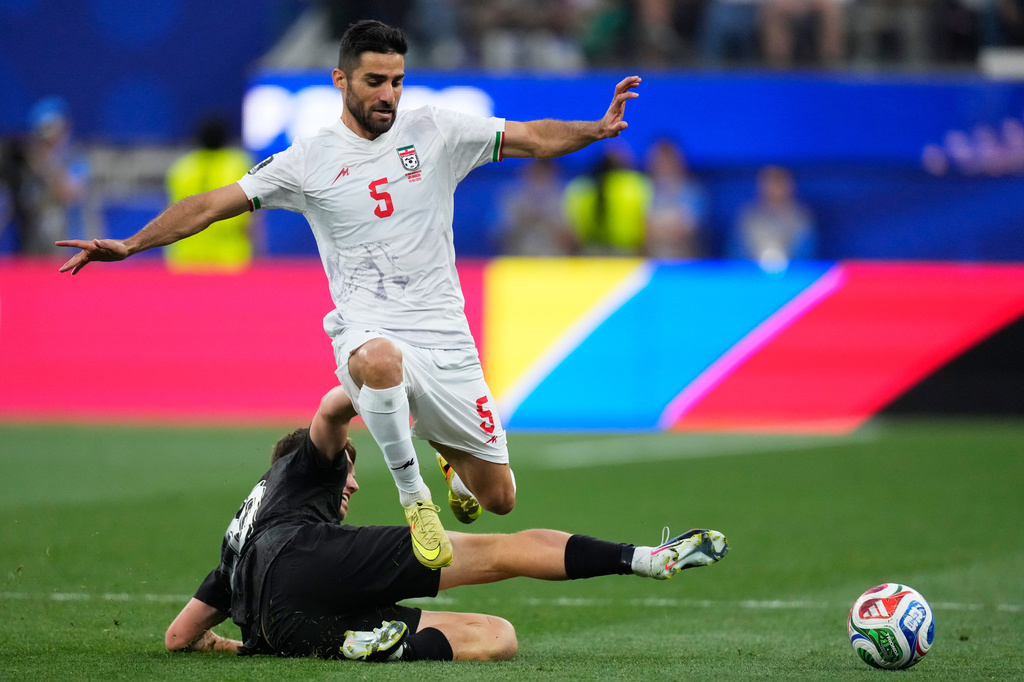 Iran's Milad Mohammadi (5) jumps over New Zealand's Callum McCowatt (20) during the World Cup Group G soccer match between Iran and New Zealand.