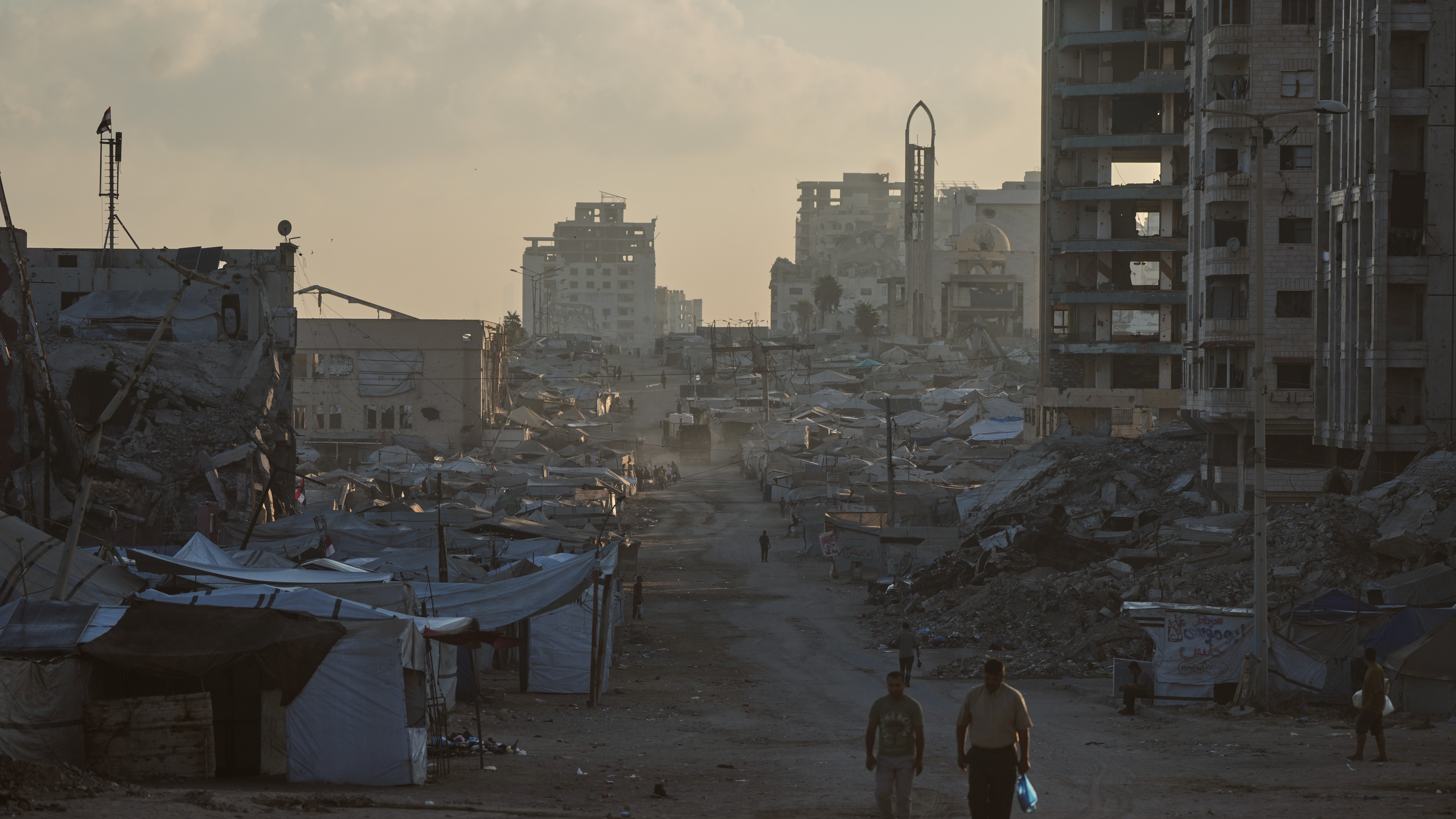 Palestinians walk along a street surrounded by buildings destroyed in Israeli military strikes during the Israel-Hamas war, in Gaza City, Thursday, July 2, 2026.