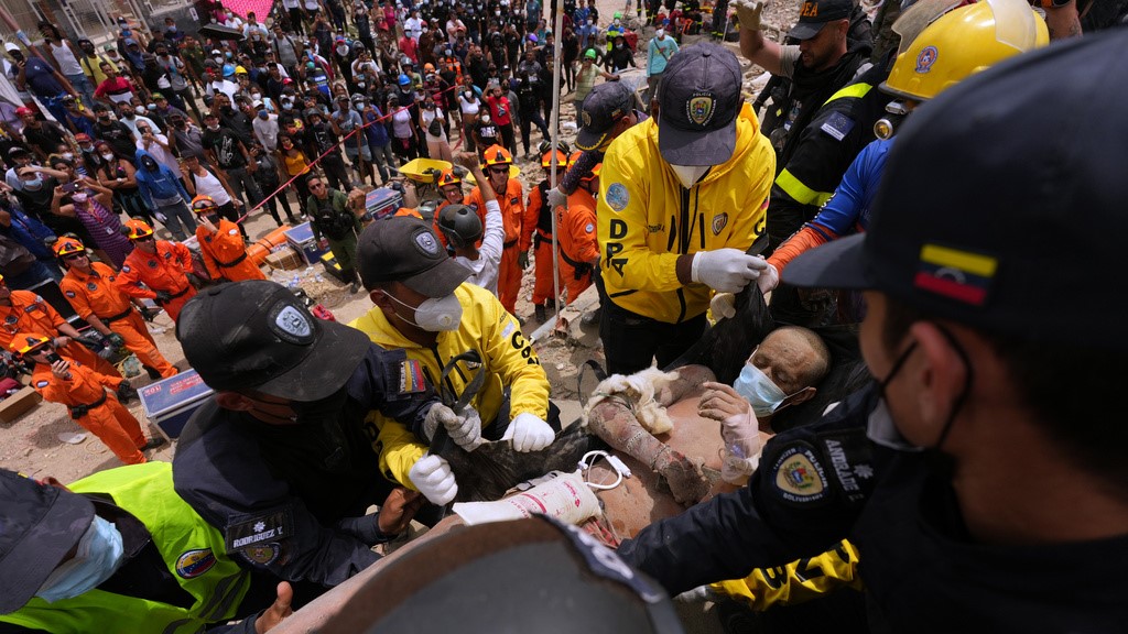 Rescue workers carry a man rescued from the rubble of a building that collapsed in the earthquakes that struck La Guaira, Venezuela.