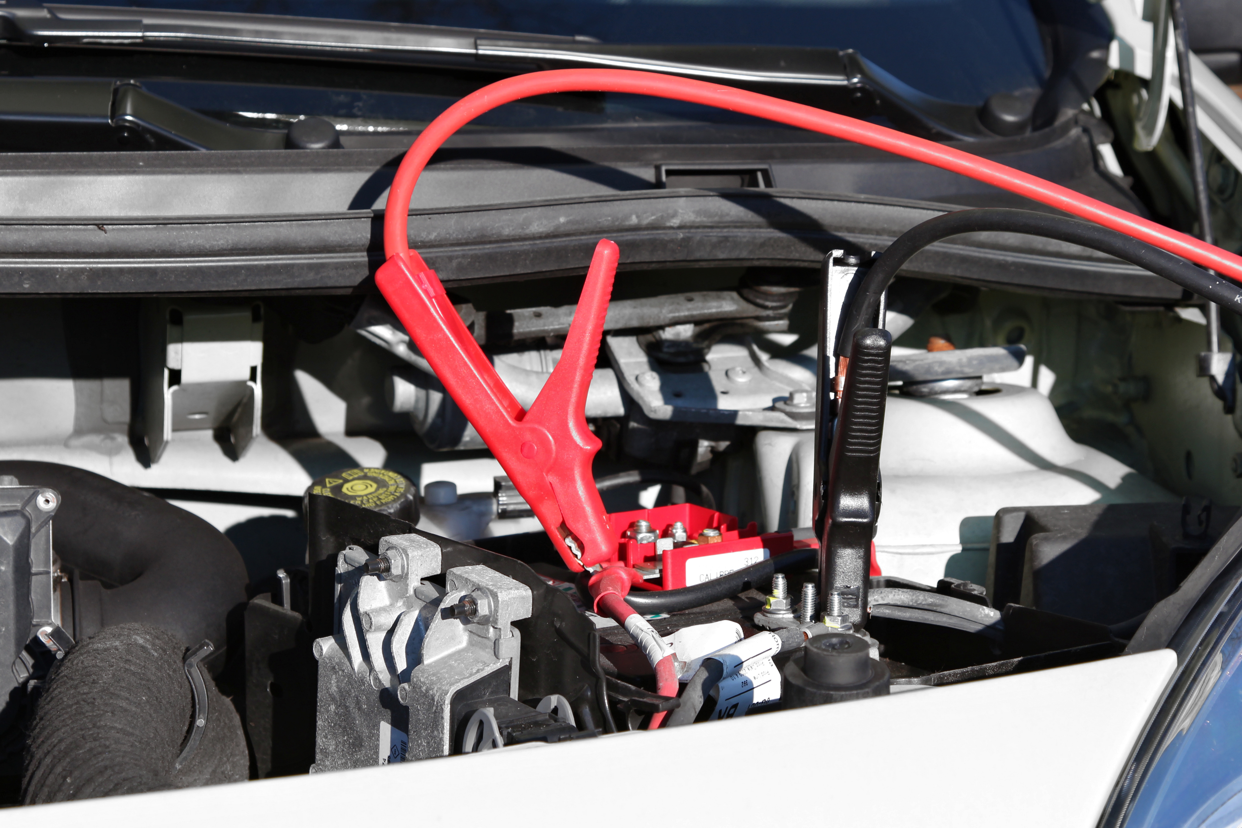A car battery with jump-leads attached. 