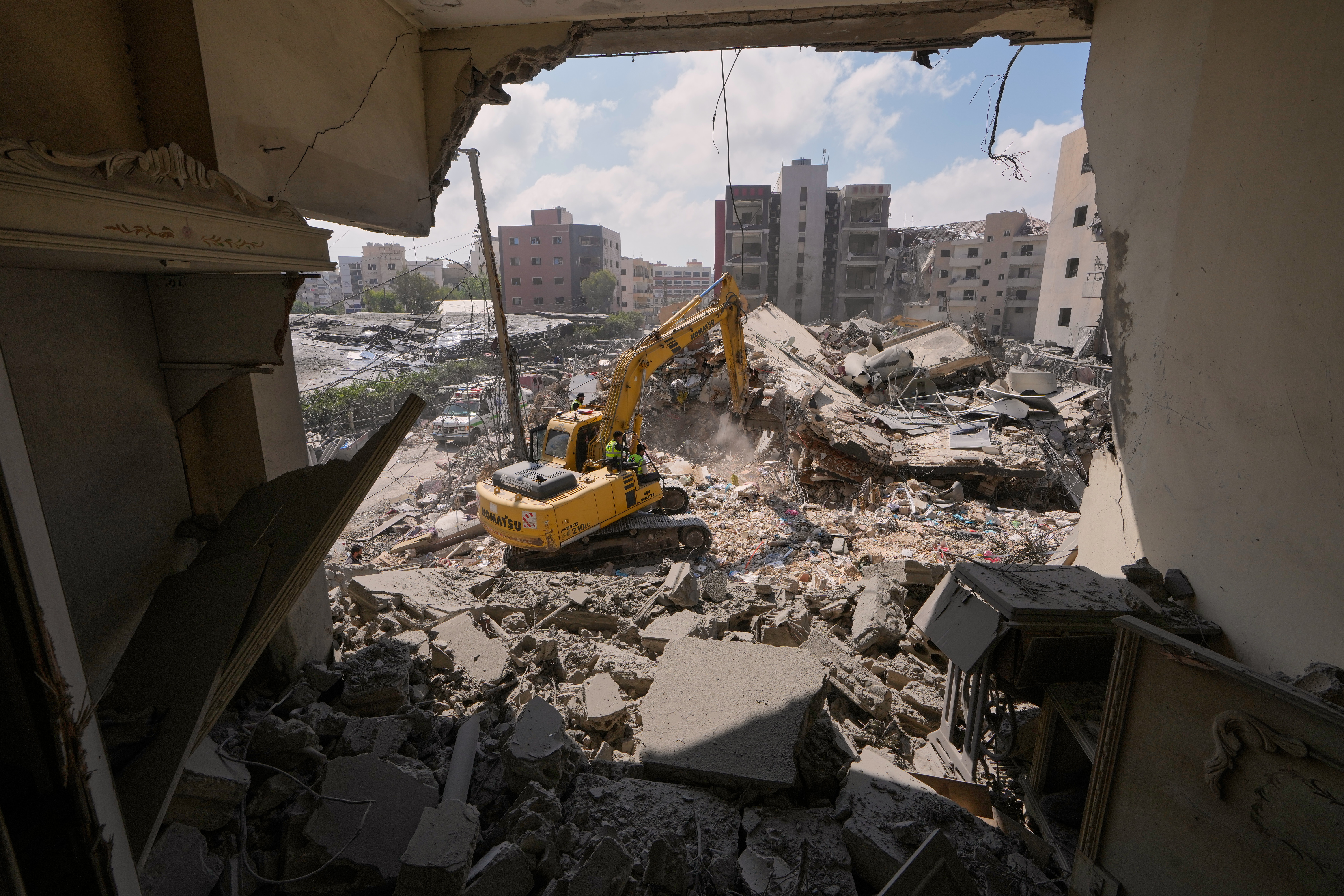 Rescue workers use an excavator, as they search for victims under the rubble of a building that was hit Monday in an Israeli airstrike 