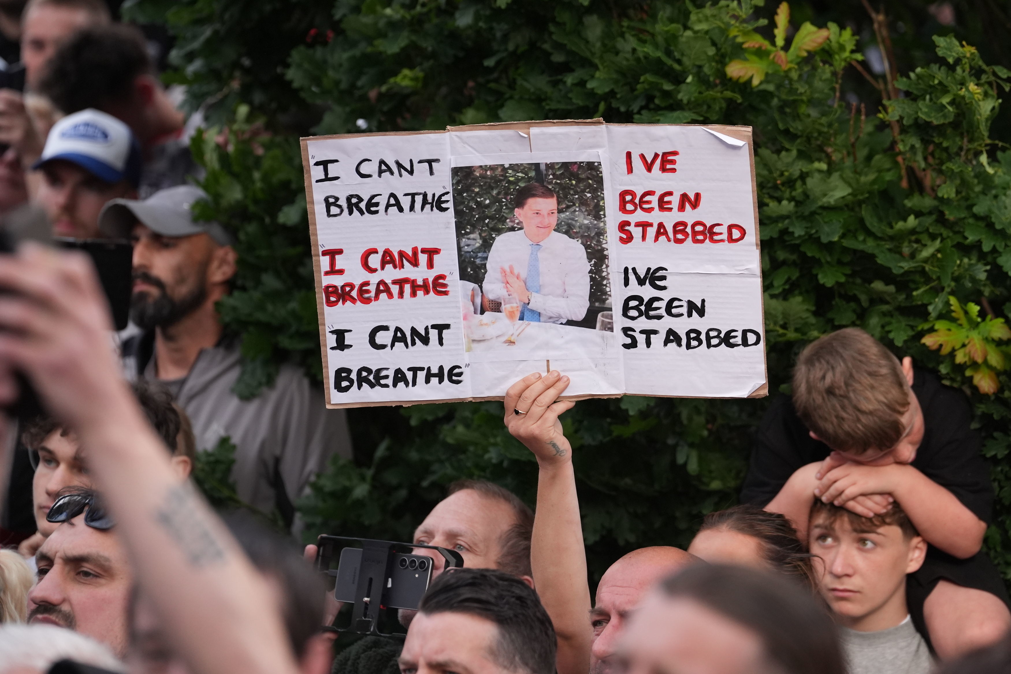 People protest outside the police station in Southampton, England, on Tuesday, June 2, 2026, one holding a photo of December 2025 stabbing victim Henry Nowak, 18. 