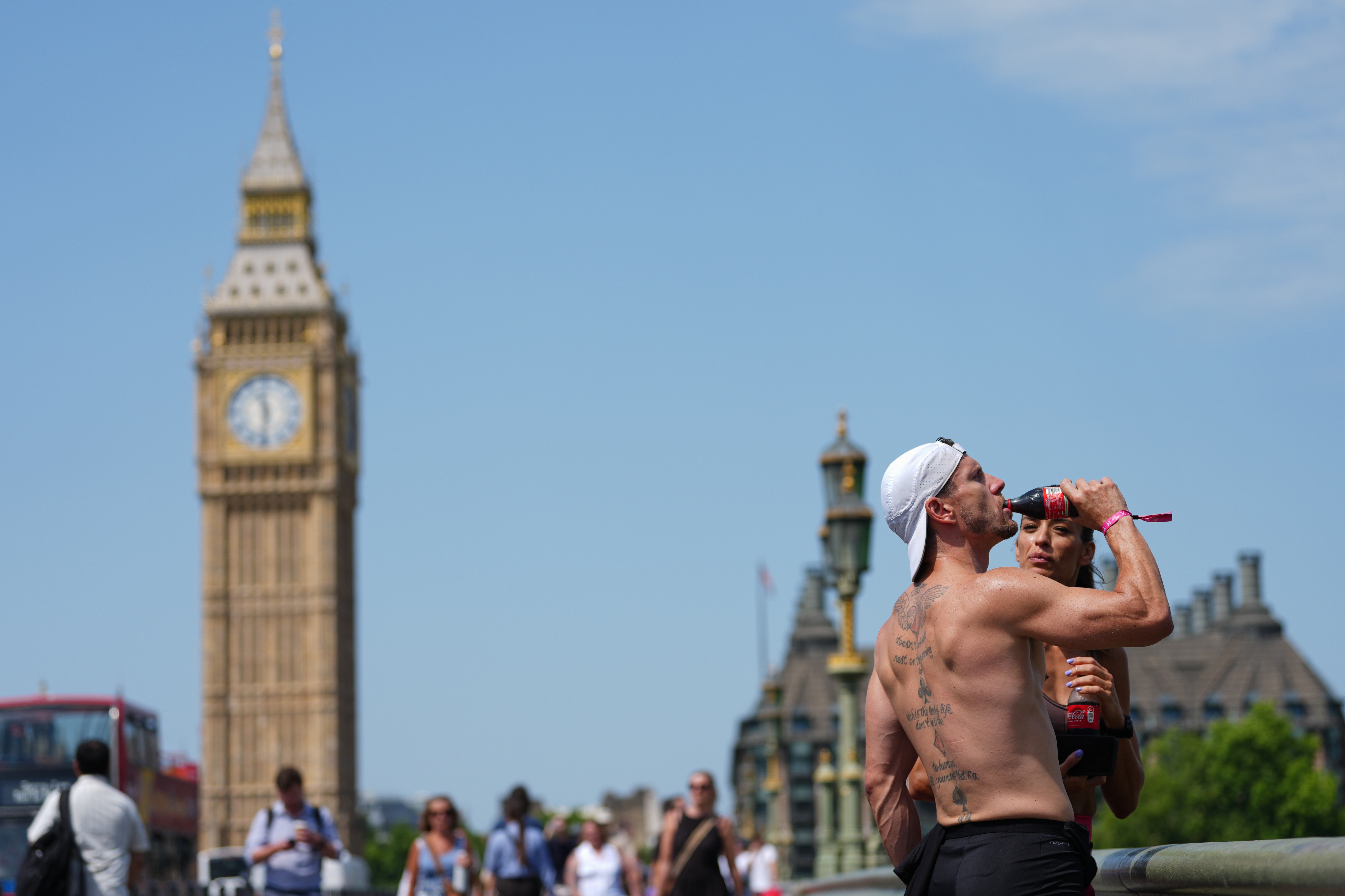 A man drinks on Westminster Bridge in London, as a heat wave is predicted Tuesday, June 23, 2026.