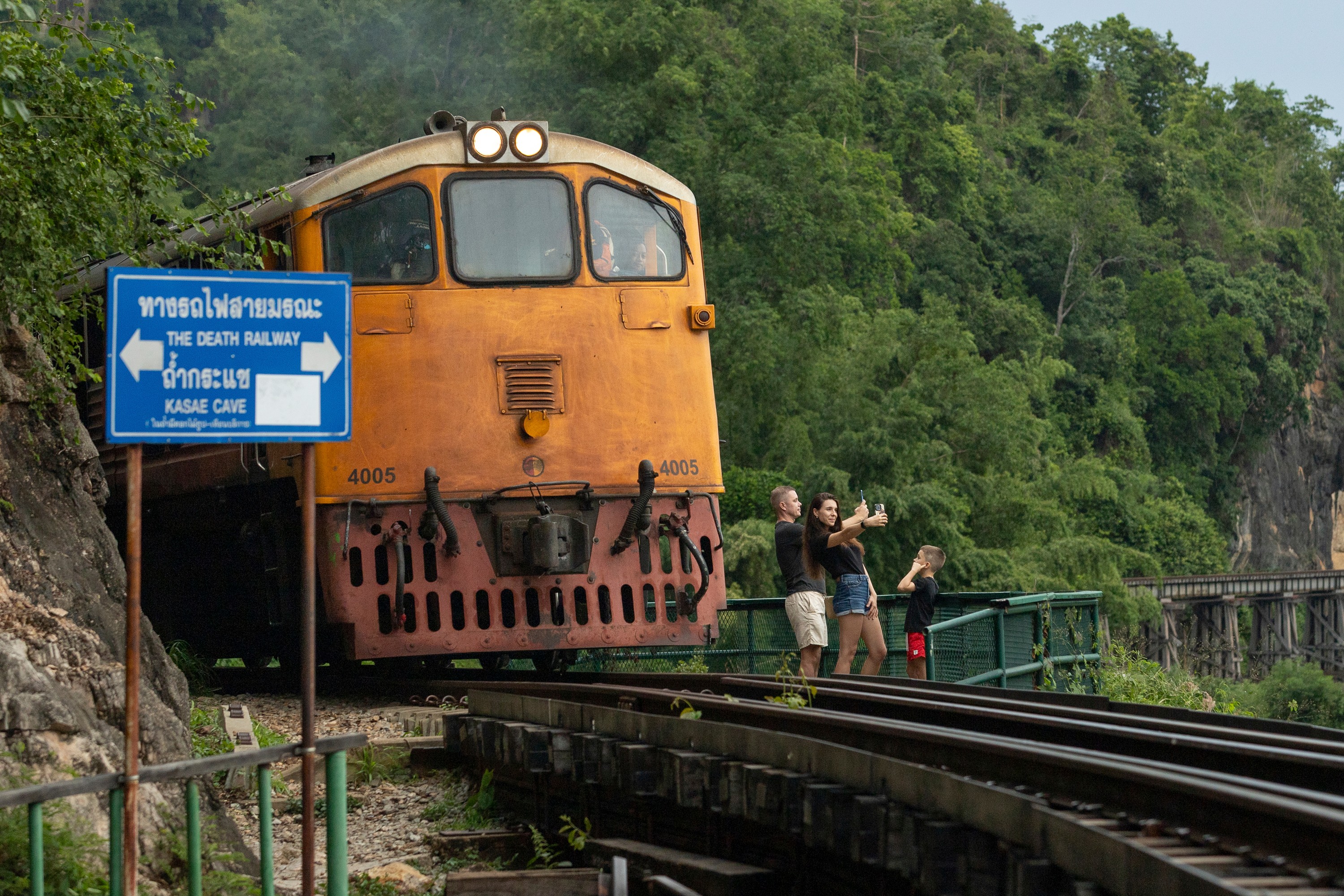 A family of Russian tourists pose for photos as a train approaches Thamkra Sae Station, one of the still active sections of the infamous World War II