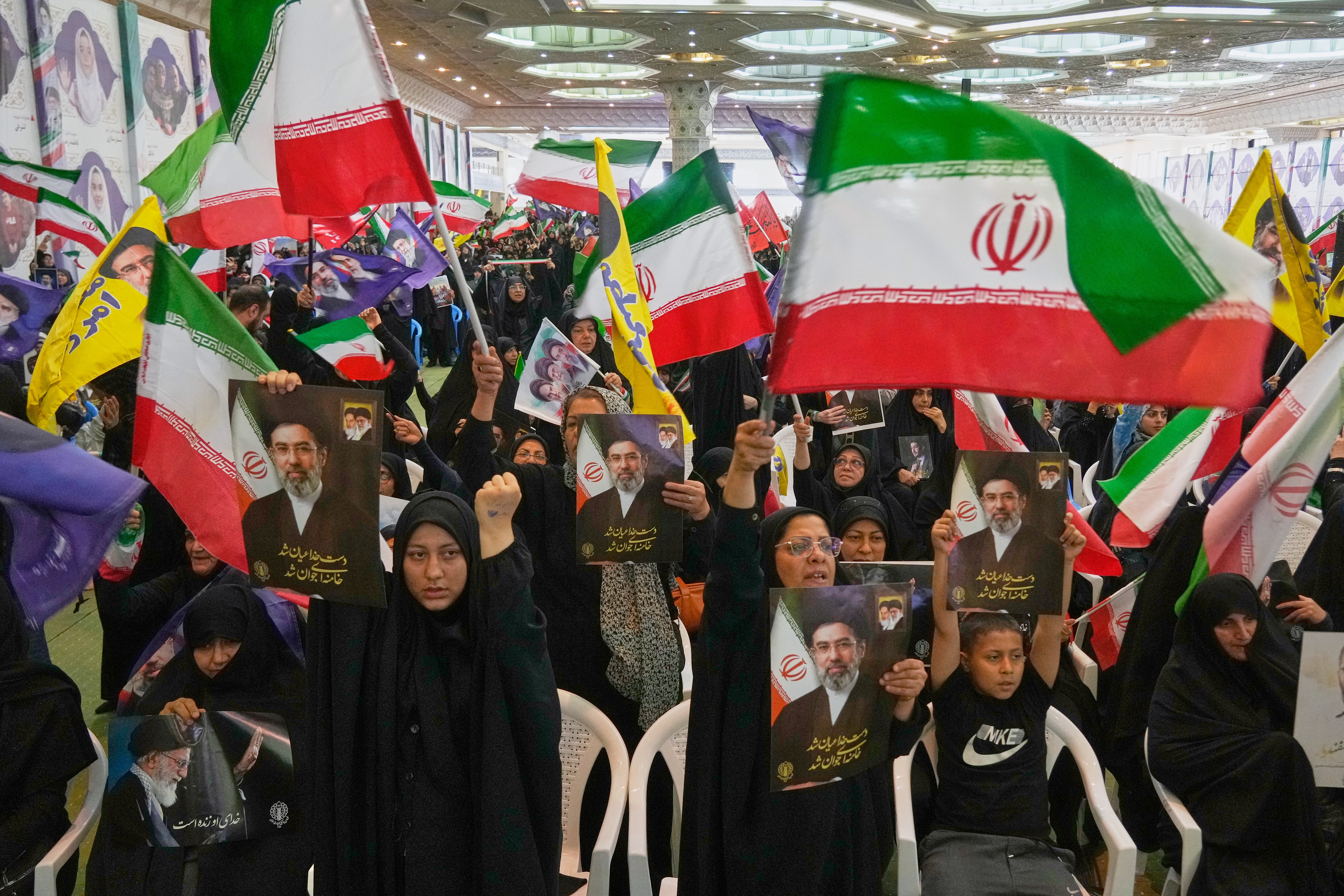 Government supporters hold Iranian flags and pictures of Iran's Supreme Leader, Ayatollah Mojtaba Khamenei