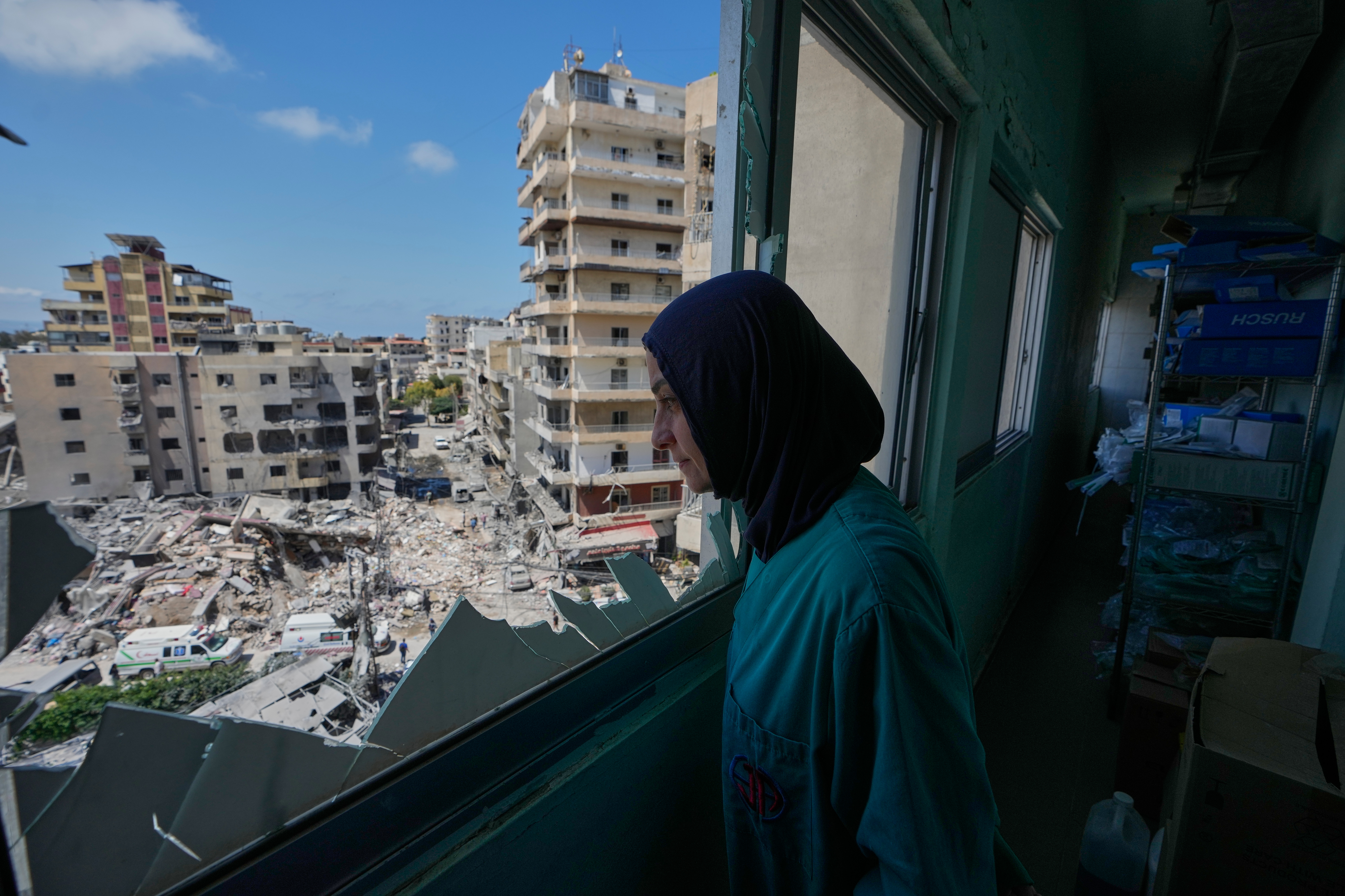 A nurse looks through a shattered window of the Jabal Amel Hospital 