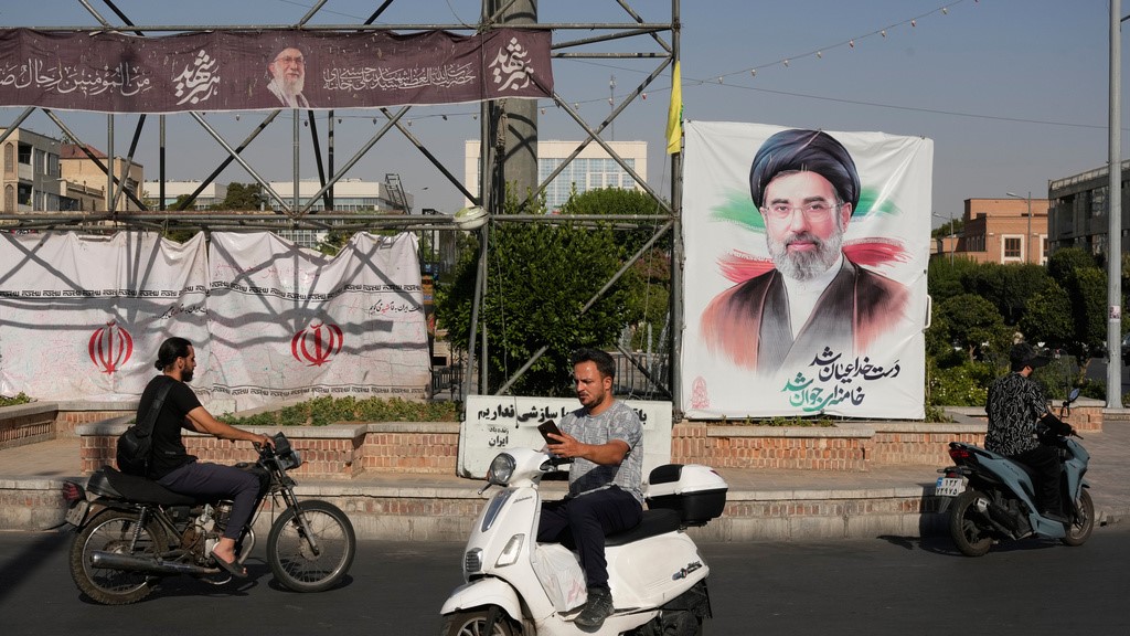 Motorbikes drive past a banner showing a portrait of the Iranian Supreme Leader Ayatollah Mojtaba Khamenei in downtown Tehran, Iran.
