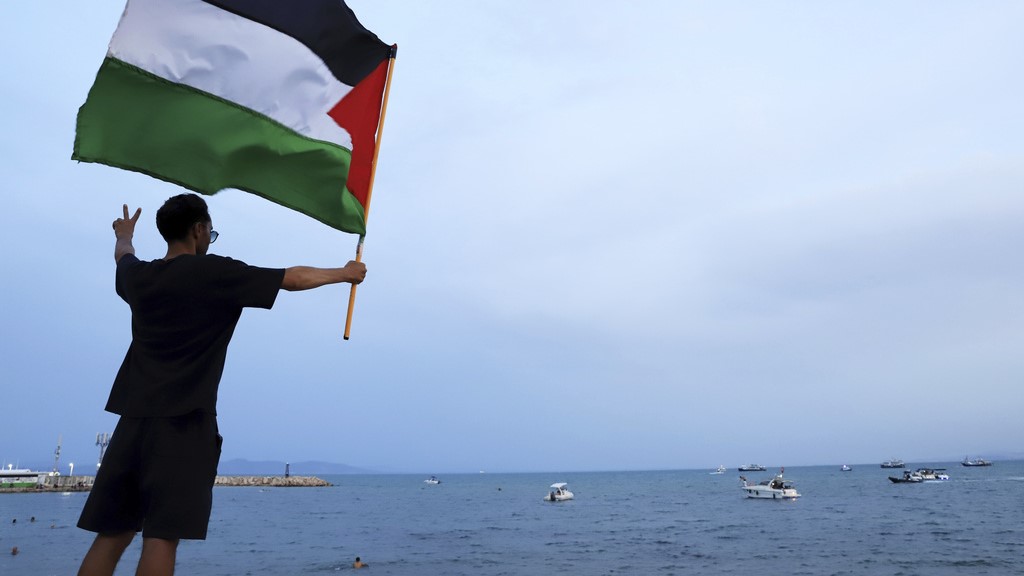 A protester waves a Palestinian flag in support of the the Global Sumud Flotilla as it arrives at the port of Sidi Bou Saïd, in Tunis, Tunisia.