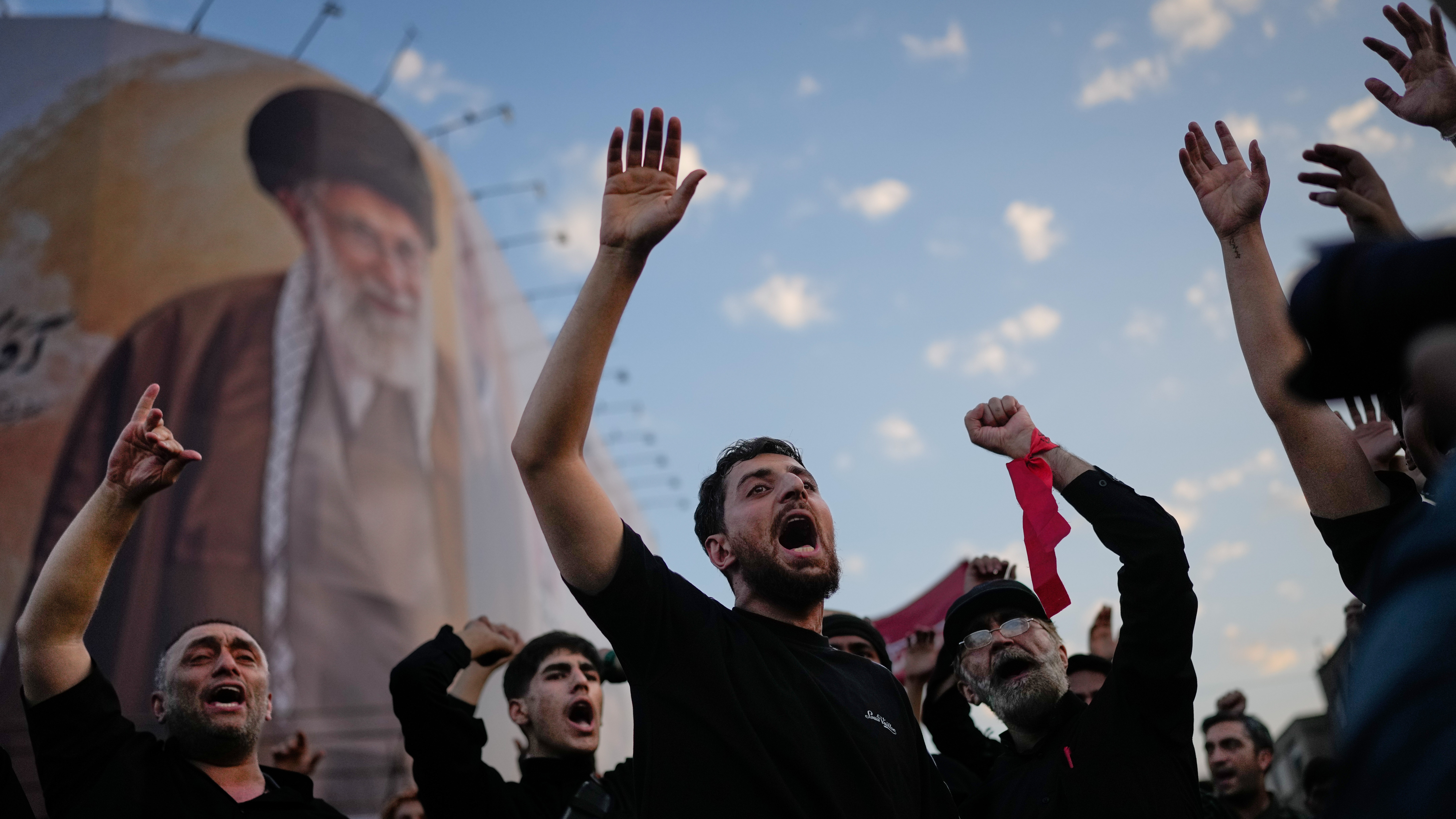 Mourners chant slogans while gathered in Islamic Revolution Square for the funeral procession of the slain Iranian Supreme Leader Ayatollah Ali Khamenei beneath a billboard depicting Khamenei in Tehran, Iran, Monday, July 6, 2026.