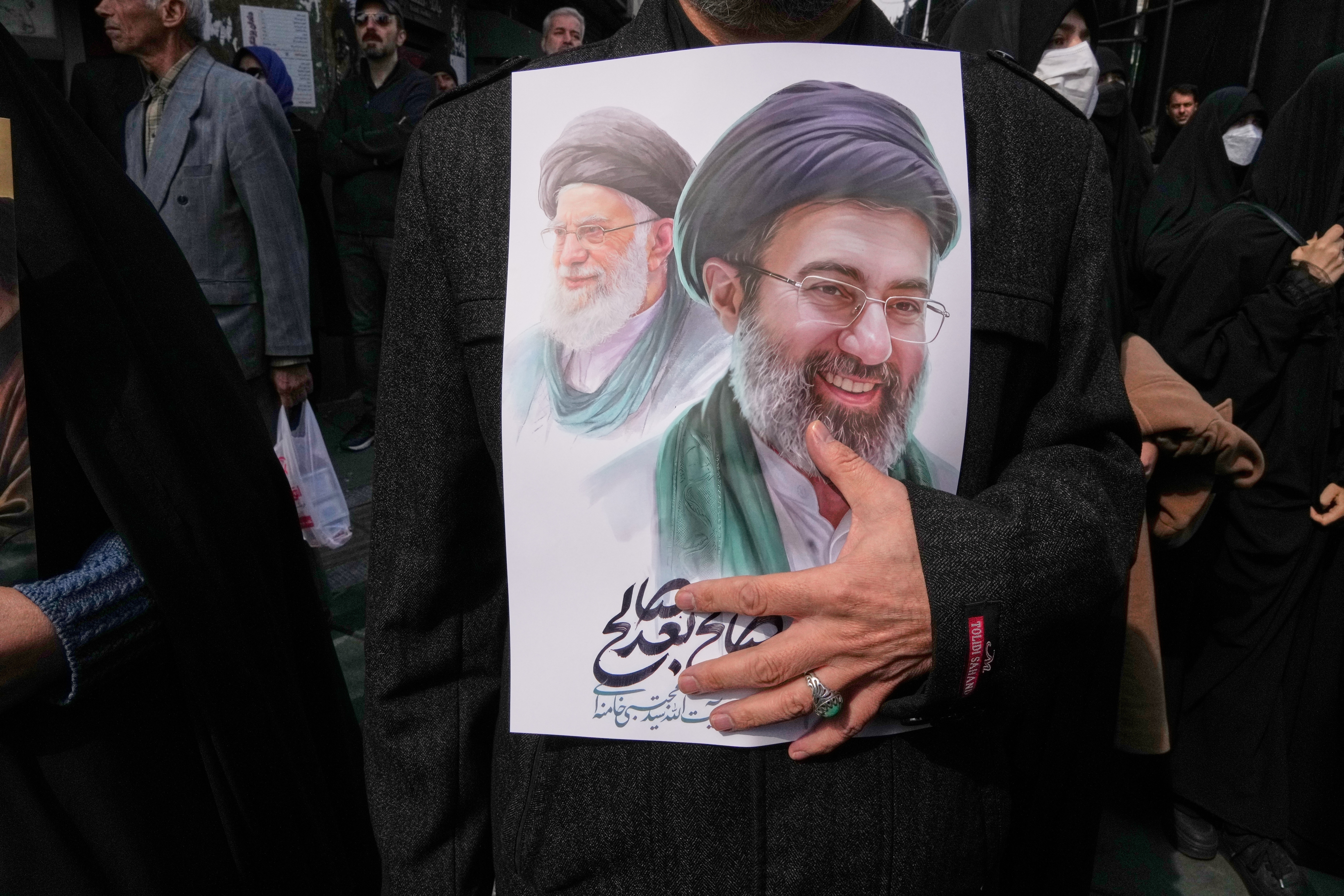 A mourner holds a poster depicting Ayatollah Mojtaba Khamenei