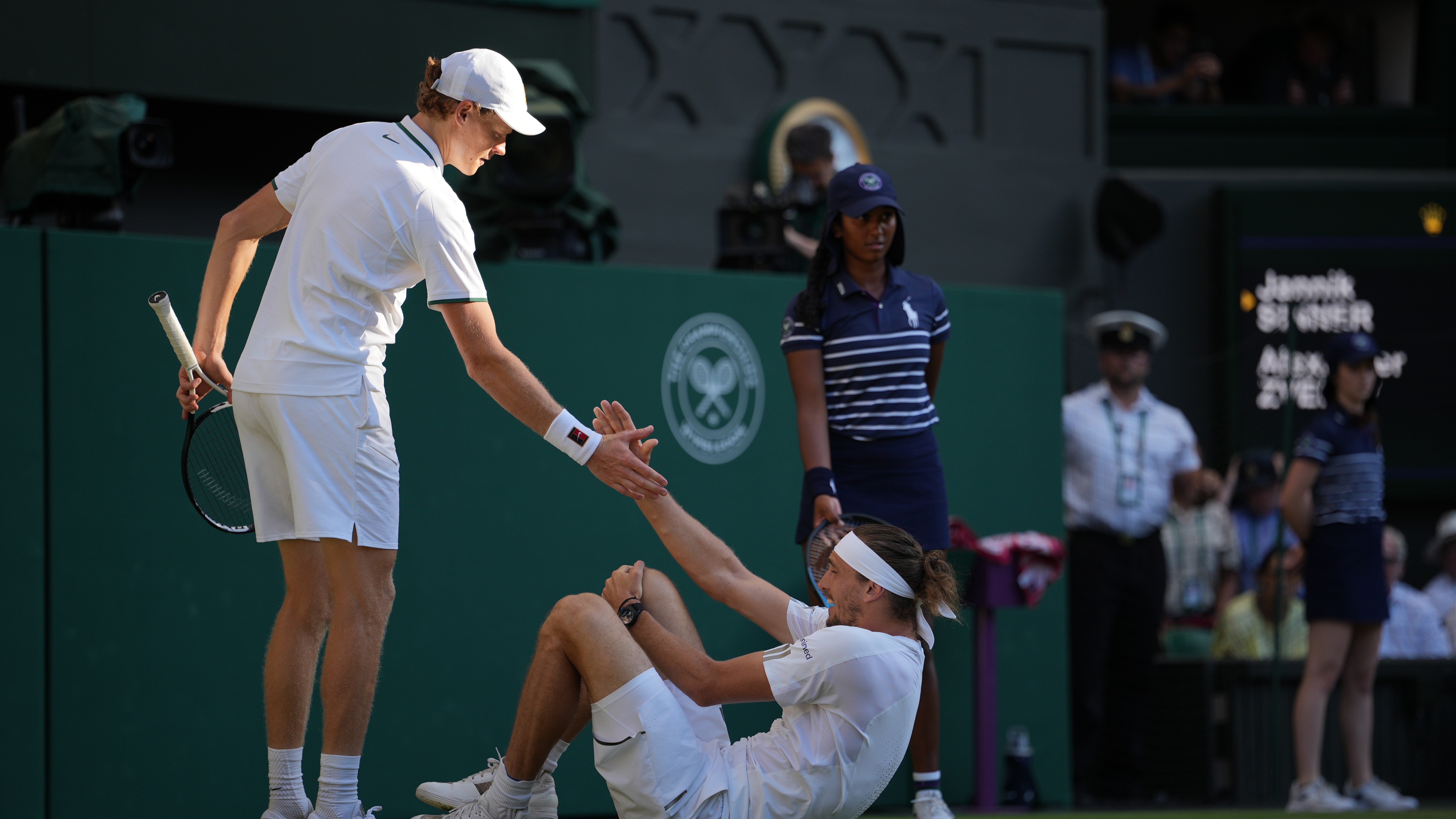 Jannik Sinner of Italy, left helps up Alexander Zverev of Germany who fell during the men's singles final at Wimbledon Tennis Championships in London.