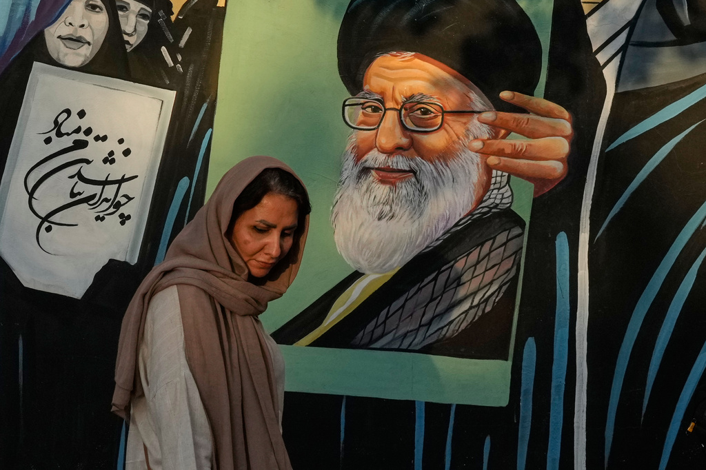 A woman walks past a mural depicting a portrait of the late Iranian Supreme Leader Ayatollah Ali Khamenei