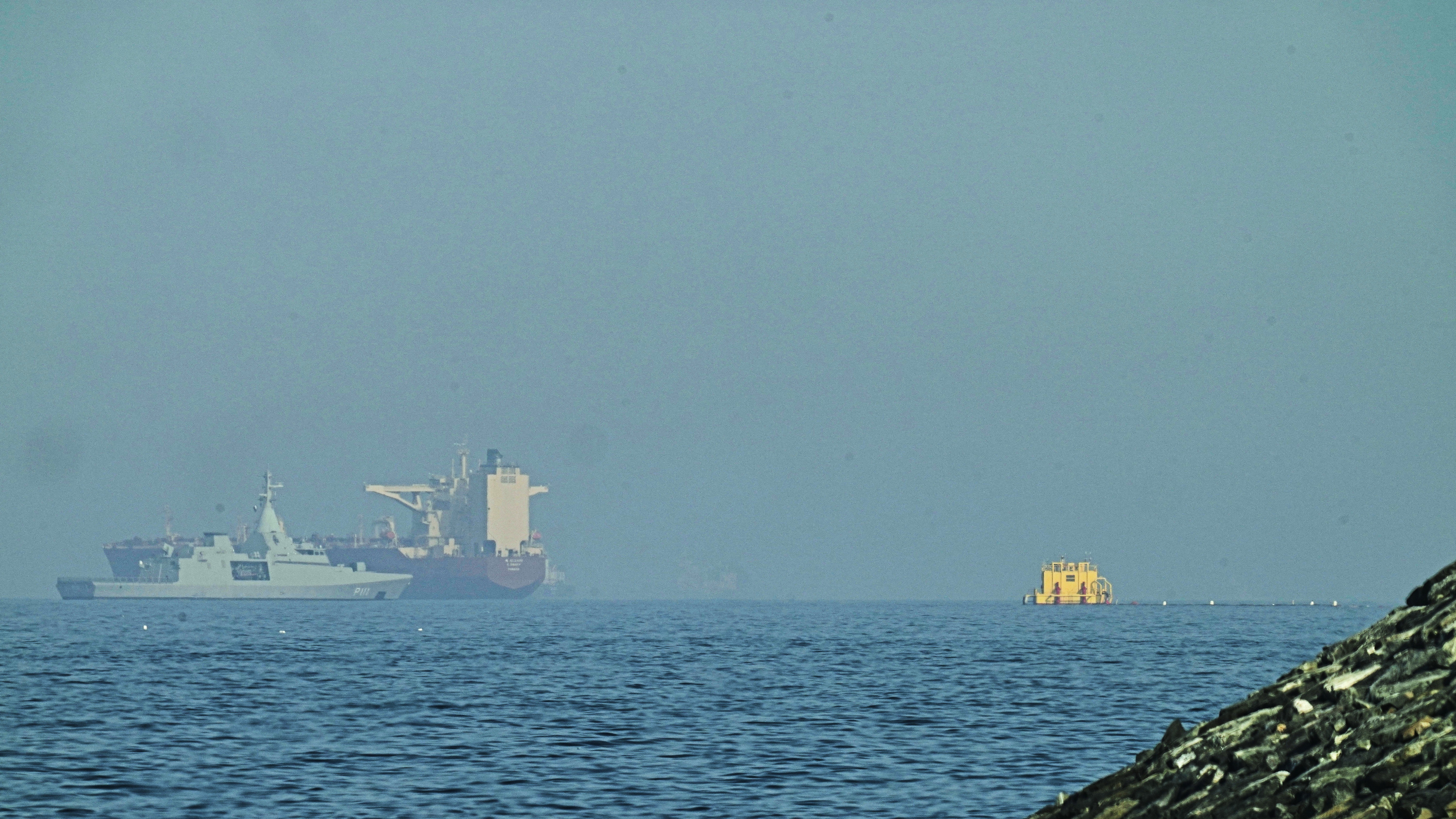 An Emirati patrol boat, left, is near a tanker anchored in the Gulf of Oman near the Strait of Hormuz, as seen from a coastal road near Khor Fakkan, United Arab Emirates, Friday, May 1, 2026.