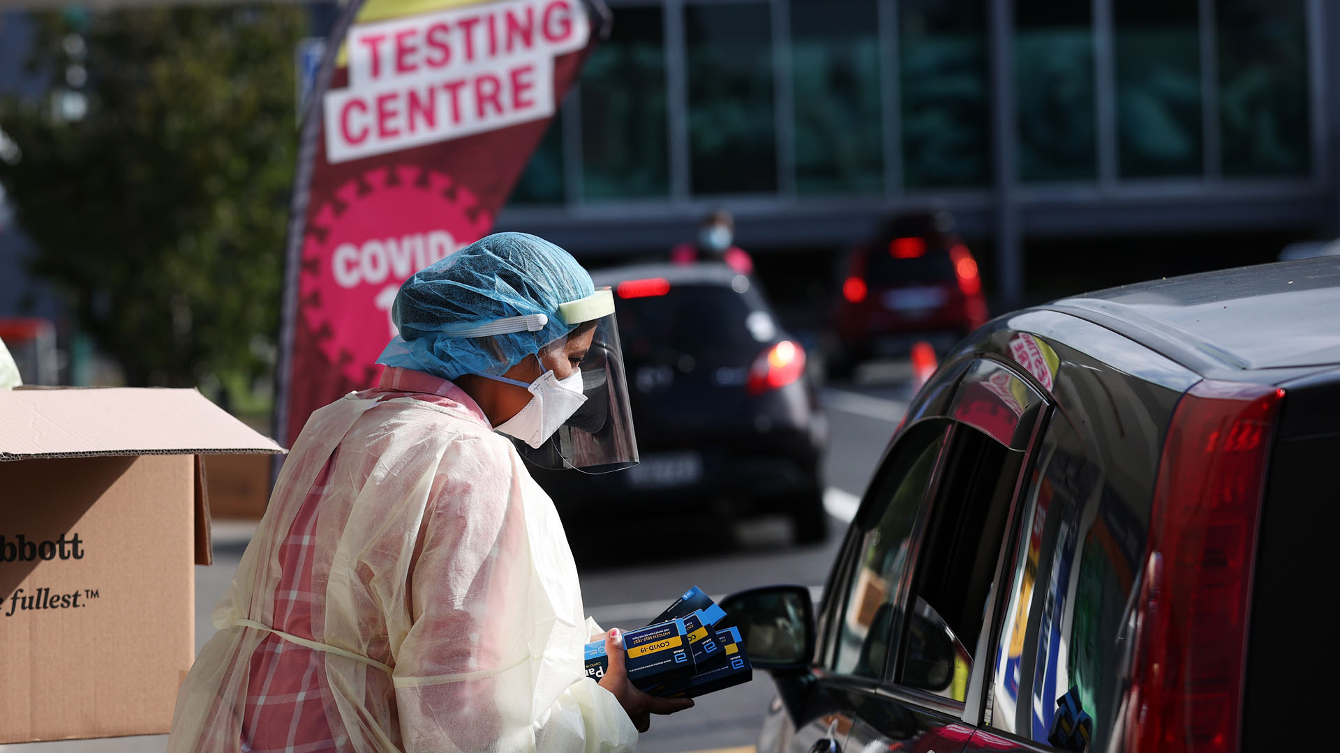 Health worker hands out rapid antigen tests at Covid-19 testing centre in Henderson, Auckland