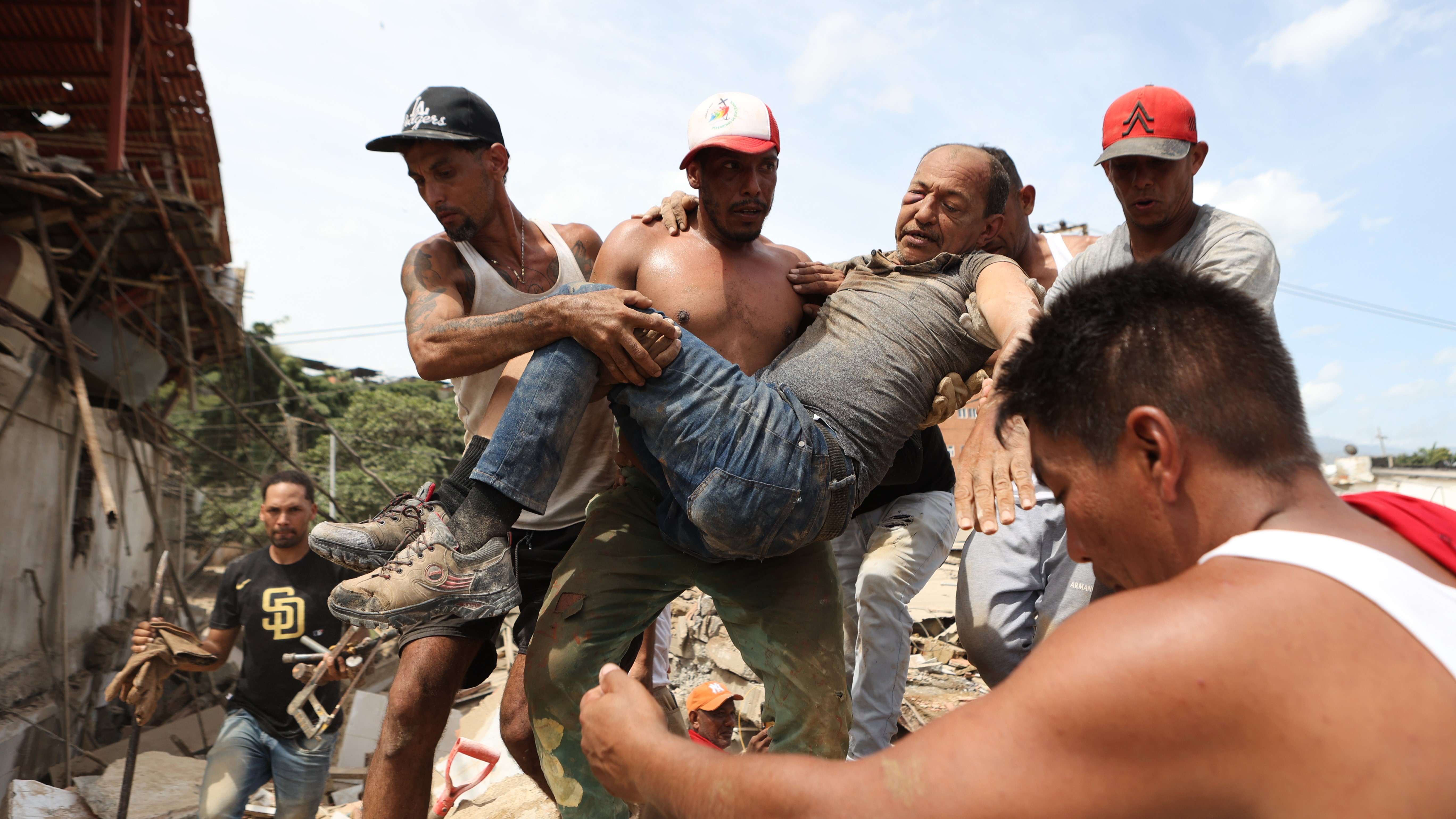 Neighbors carry a man rescued from the rubble of a collapsed building the day after earthquakes struck La Guaira, Venezuela.