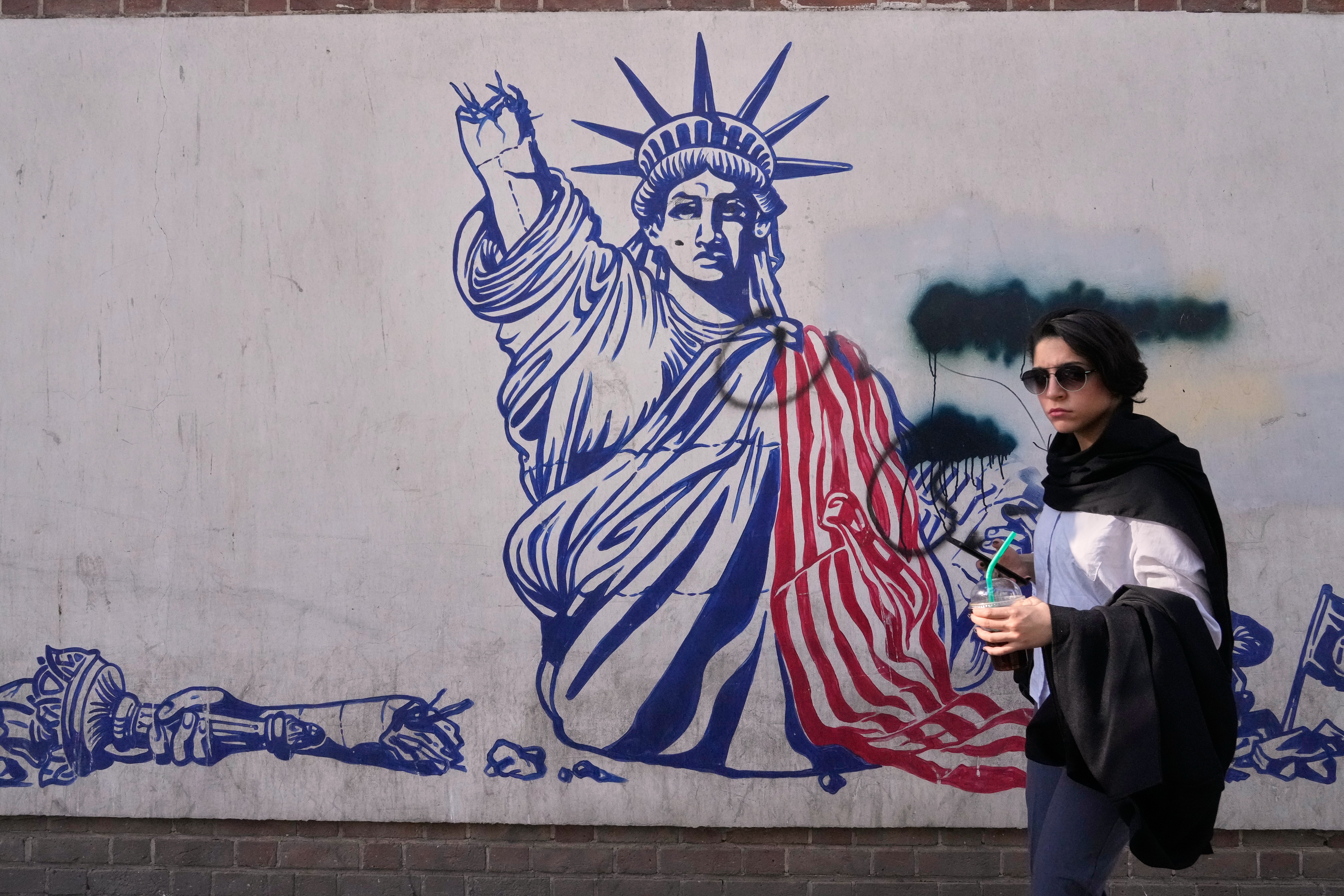 A woman walks past an anti-American mural on the wall of the former US Embassy, now a museum, in Tehran, Iran, Friday, June 12, 2026.