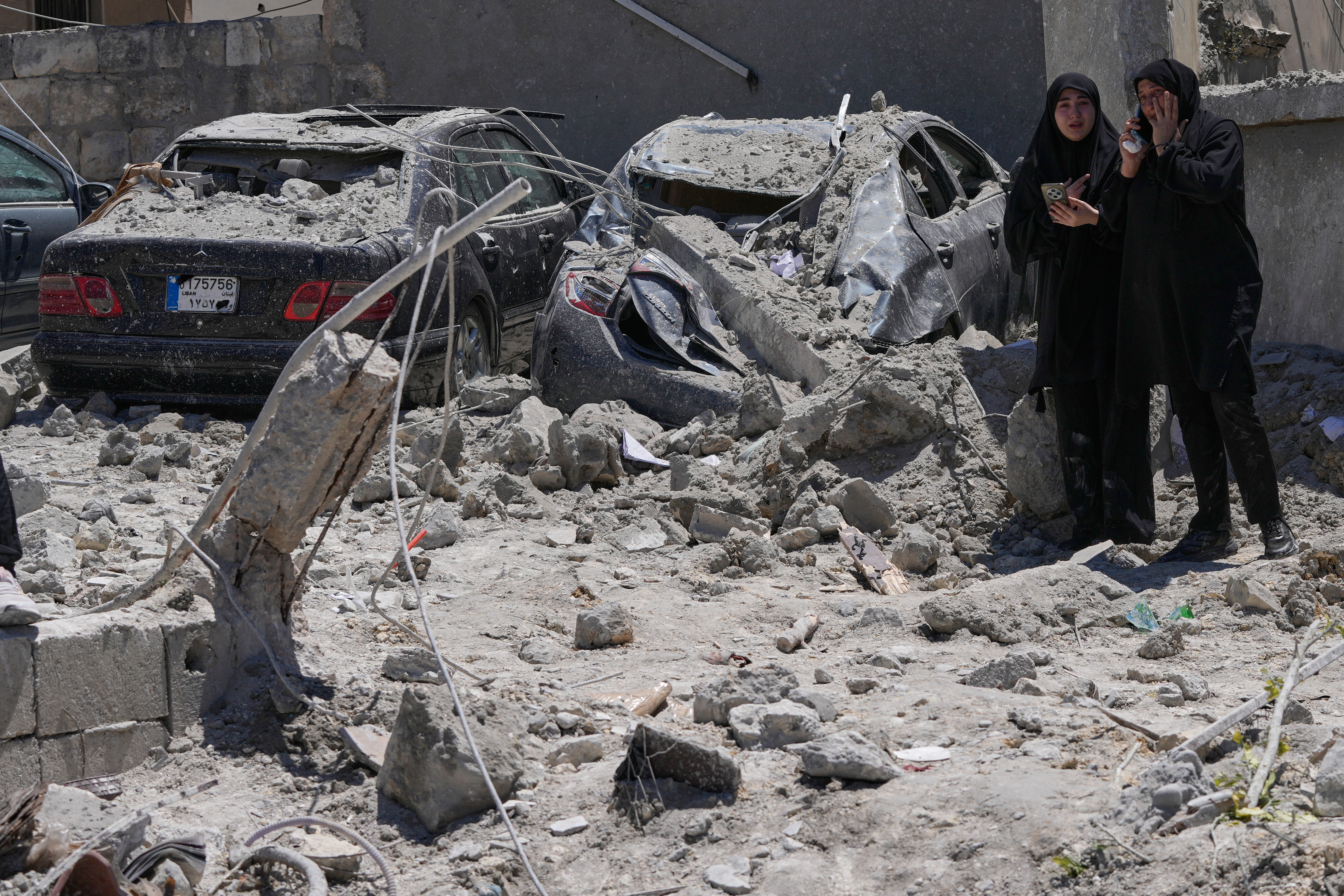 Relatives of missed victims weep, as they gather at the site of destroyed buildings that were hit in an Israeli airstrike in Qannarit village