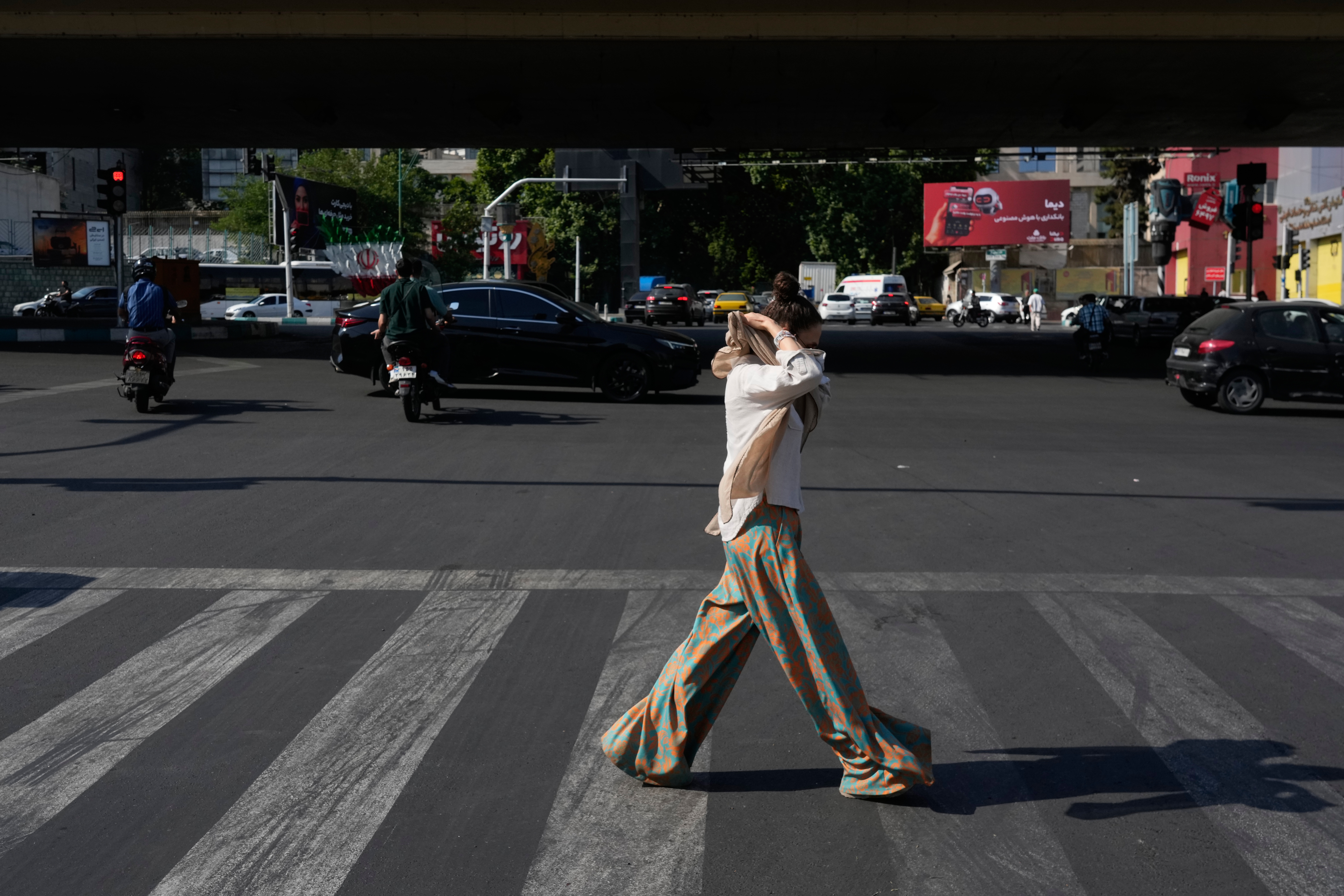 A woman adjusts her headscarf as she crosses an intersection in northern Tehran, Wednesday, June 10, 2026. 