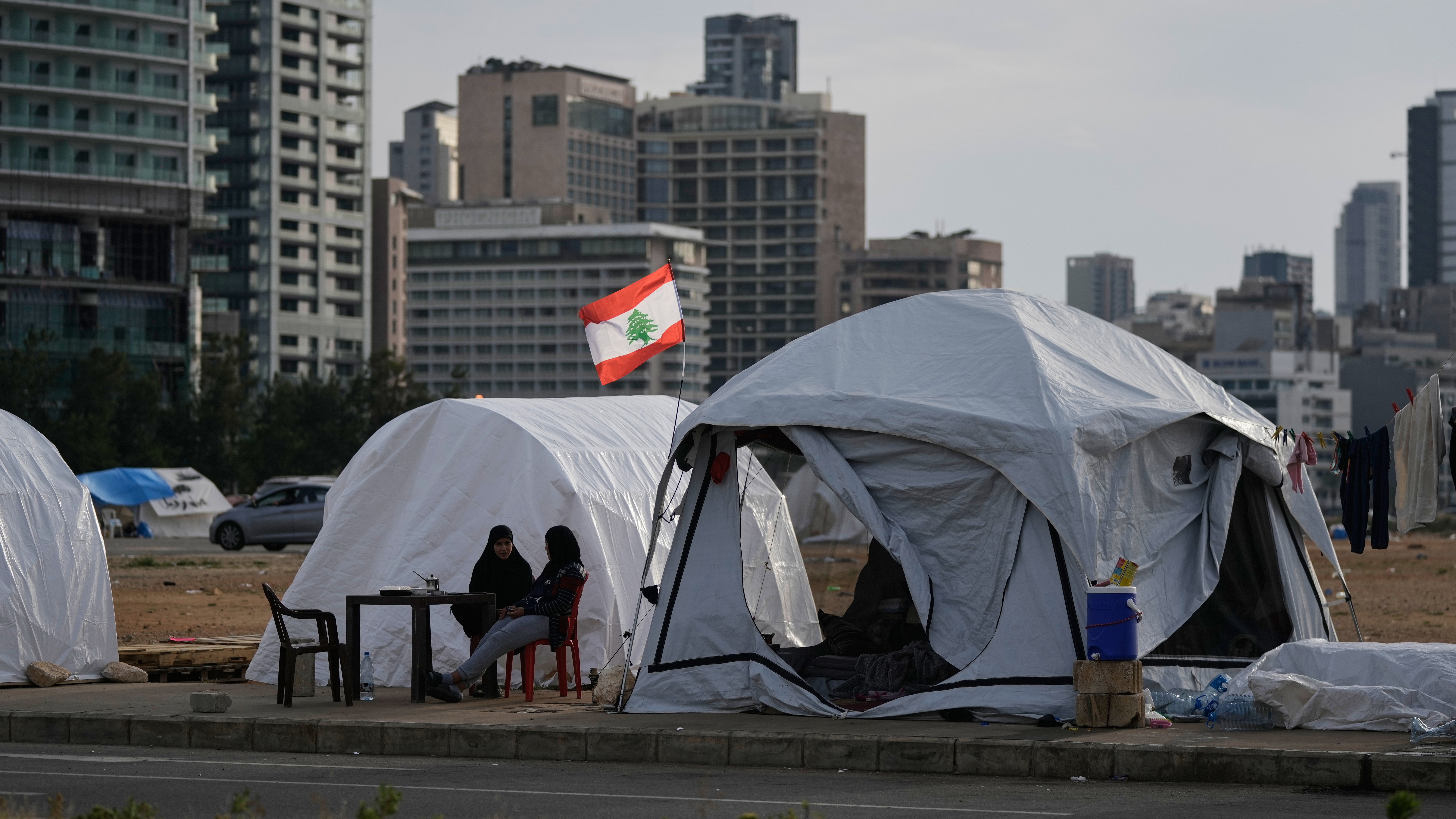Displaced people who fled Israeli strikes in southern Lebanon sit outside shelter tents in Beirut, April 24, 2026.