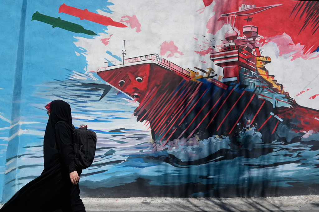 A woman walks past a mural depicting a US aircraft carrier under missile attack in downtown Tehran, Iran, Monday, June 8, 2026.