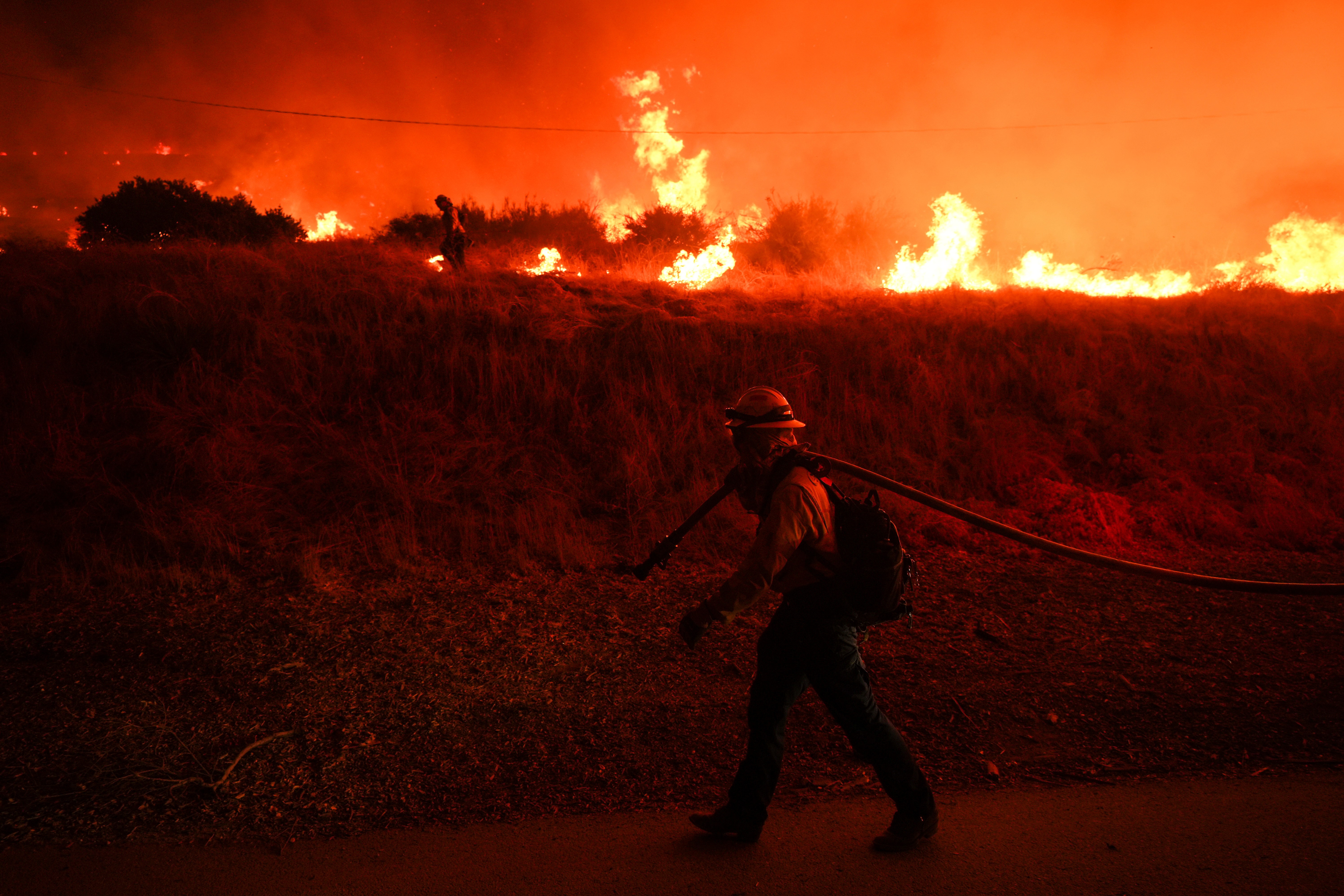 A firefighter monitors flames caused by the Hughes Fire along Castaic Lake in Castaic, California. 