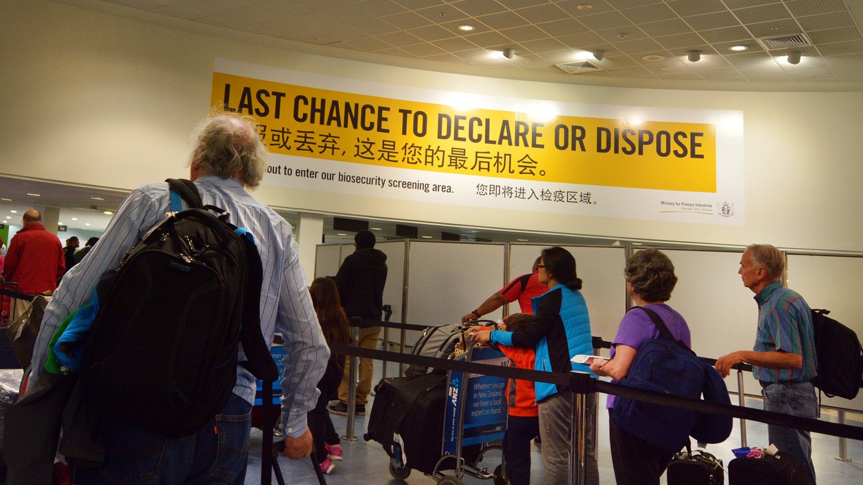 Passengers under Biosecurity sign in Auckland AIrport