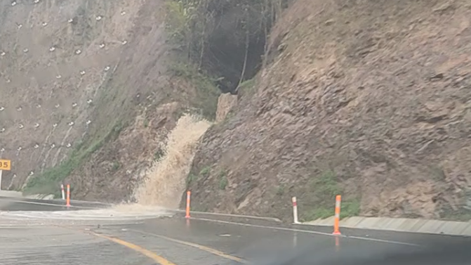 Water spills onto the road on the Brynderwyns in heavy rain.