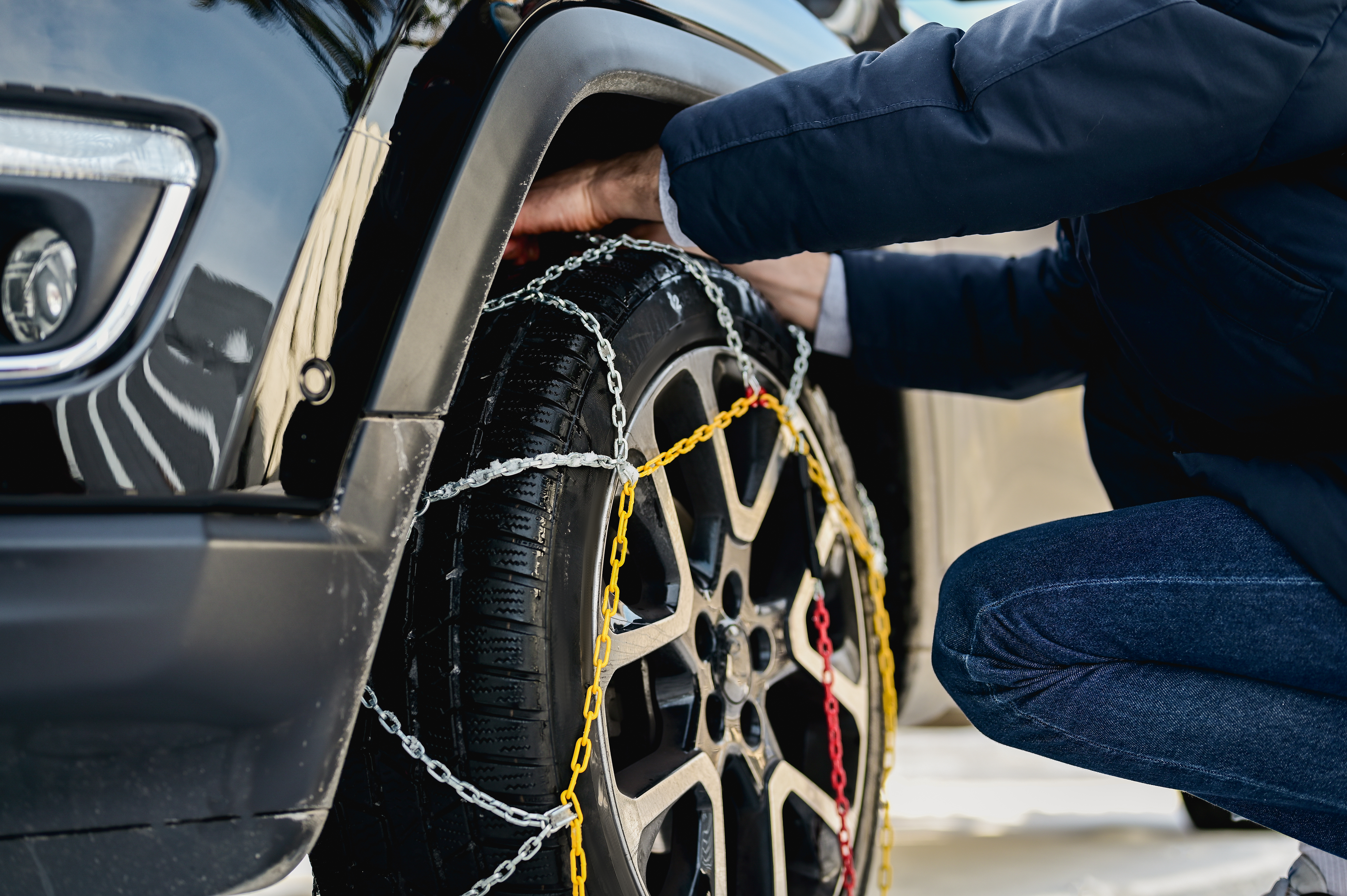 Snow chains are equipped on a car tyre. 