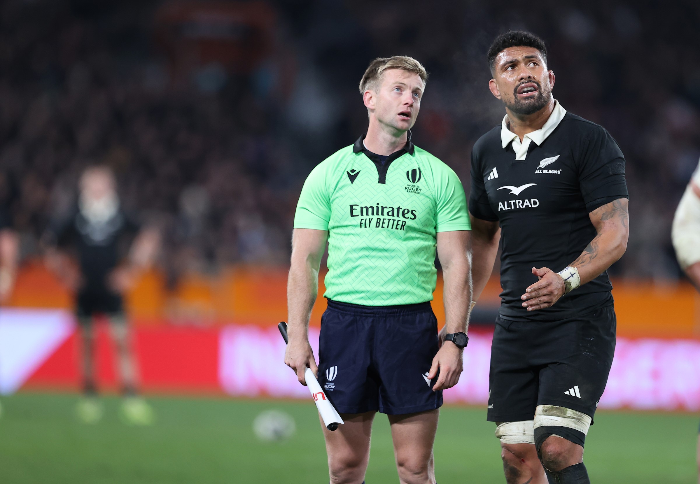 Touch judge Christophe Ridley and acting captain Ardie Savea look at a replay of Will Jordan's disallowed try against France..