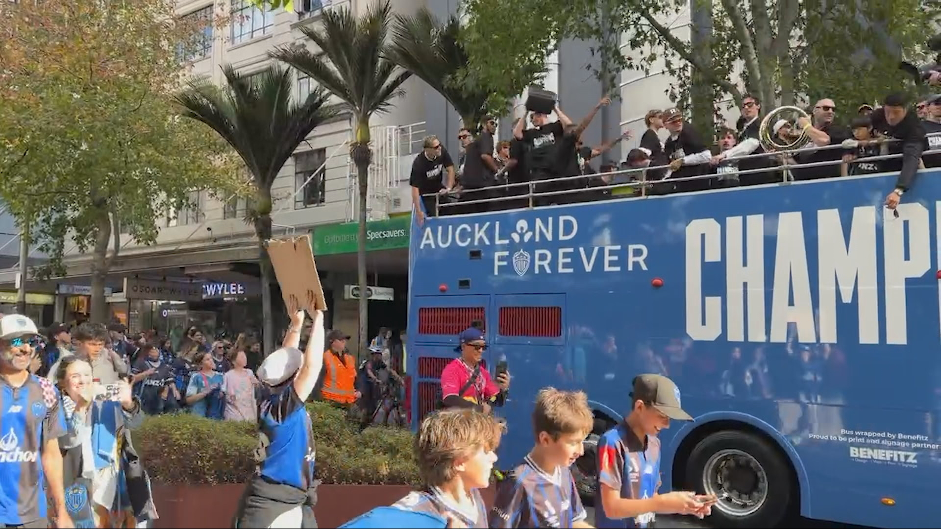 Auckland FC players parade in open-top bus.