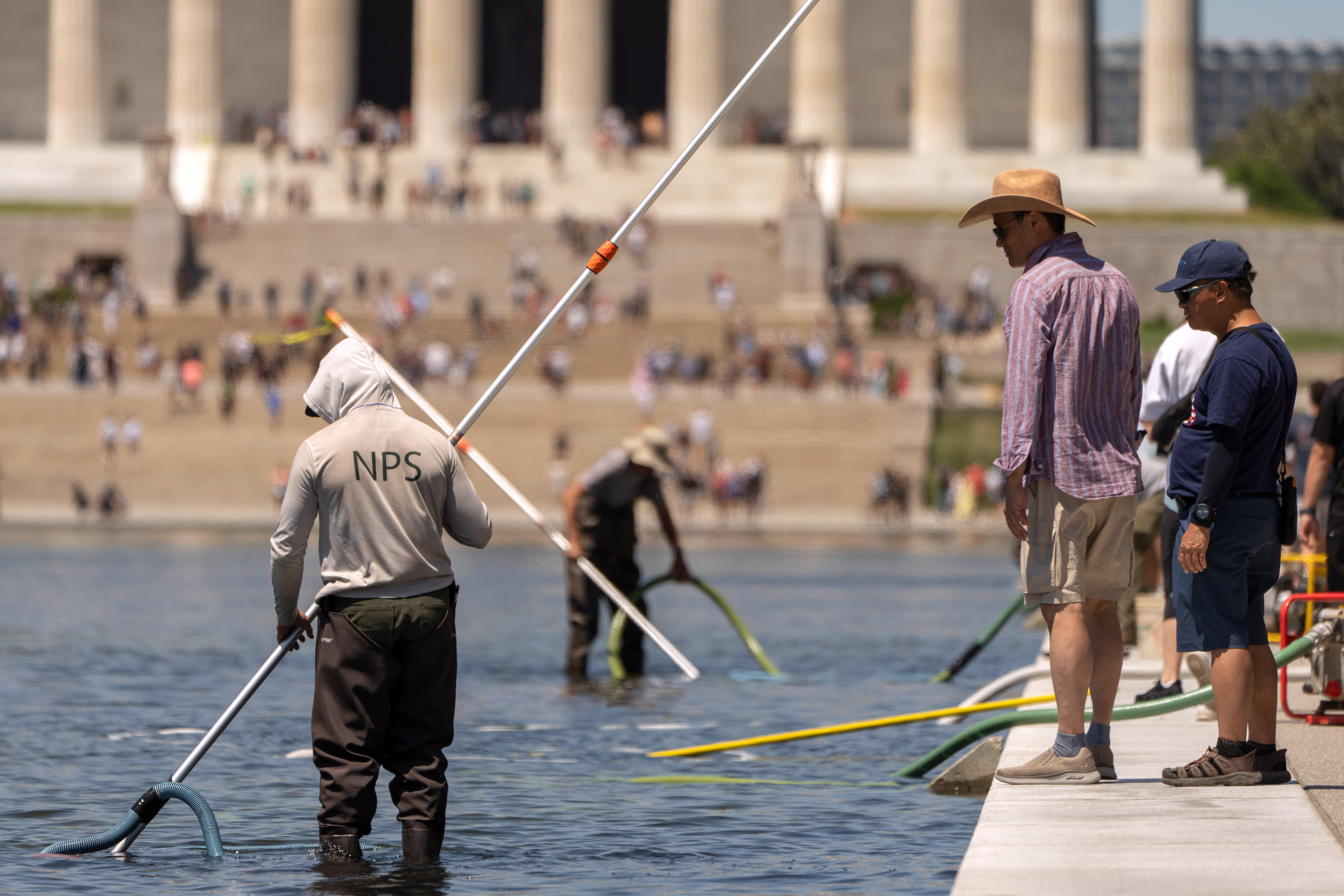 Visitors watch as National Park Service employees use vacuums to clean the Lincoln Memorial Reflecting Pool, Saturday, June 20, 2026, in Washington