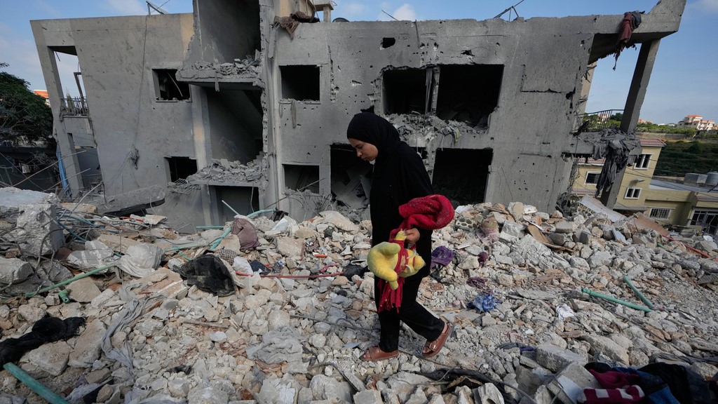 A resident carries belongings as she walks through the rubble of her home destroyed in an Israeli airstrike a day earlier in the southern village of Maarakeh, Lebanon, Wednesday, May 27, 2026. 