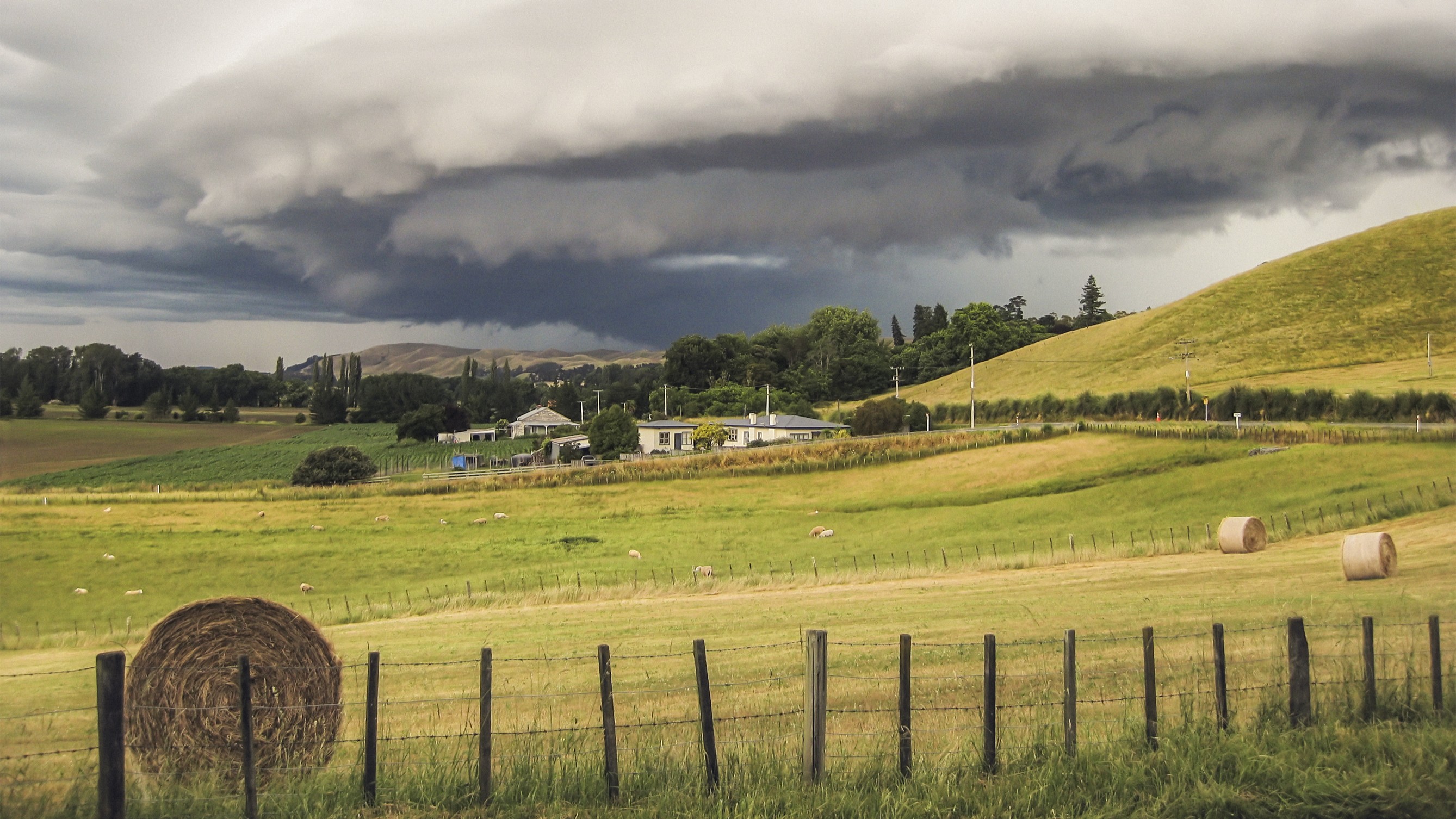 A thunderstorm brewing over hills in rural New Zealand.