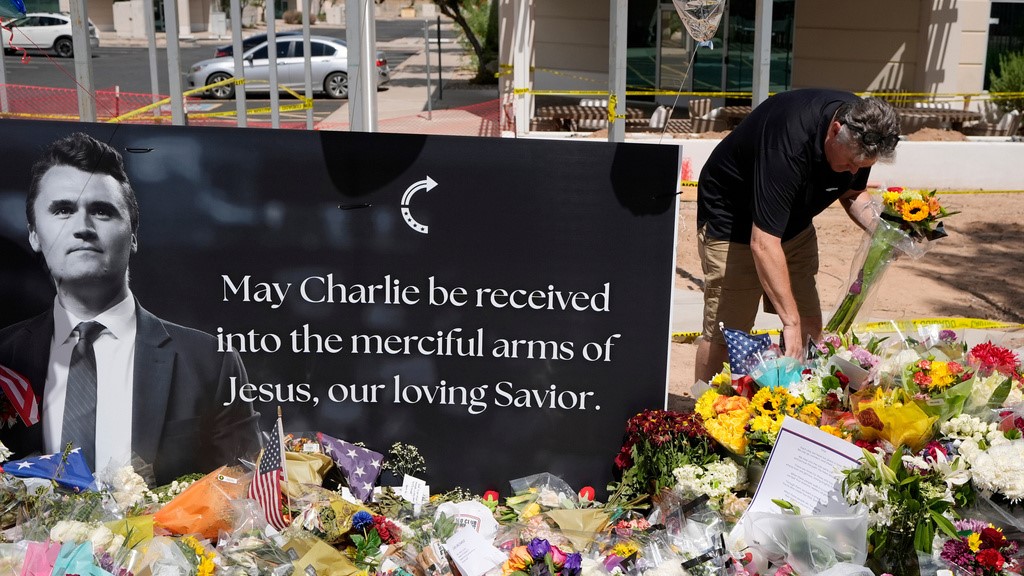 A well-wisher places flowers at a makeshift memorial set up for Charlie Kirk at Turning Point USA headquarters, September 11, 2025, in Phoenix.